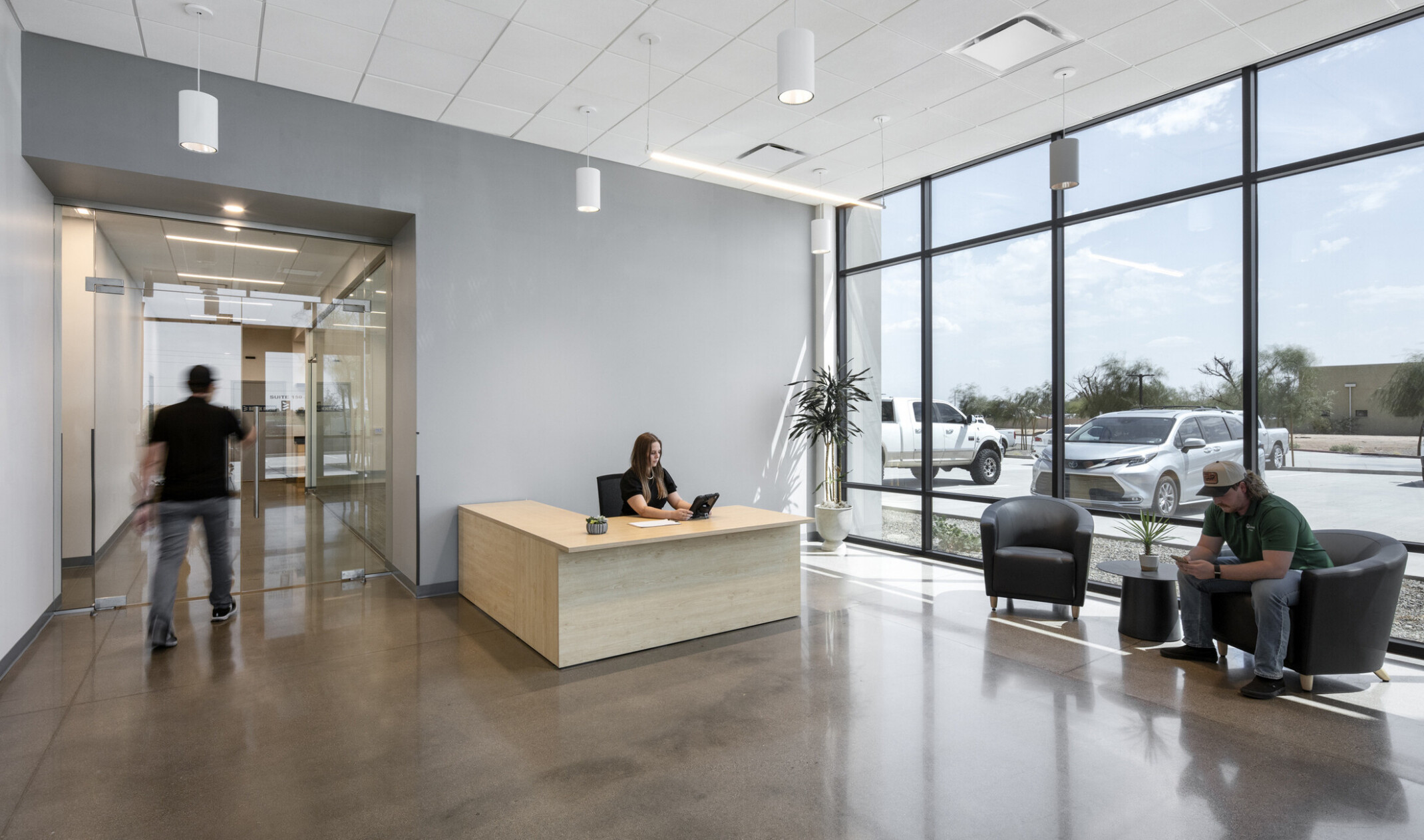 Wildeck reception area; light gray accent walls with light oak reception desk; polished concrete flooring; guest seating grouping; floor-to-ceiling windows bringing in natural light