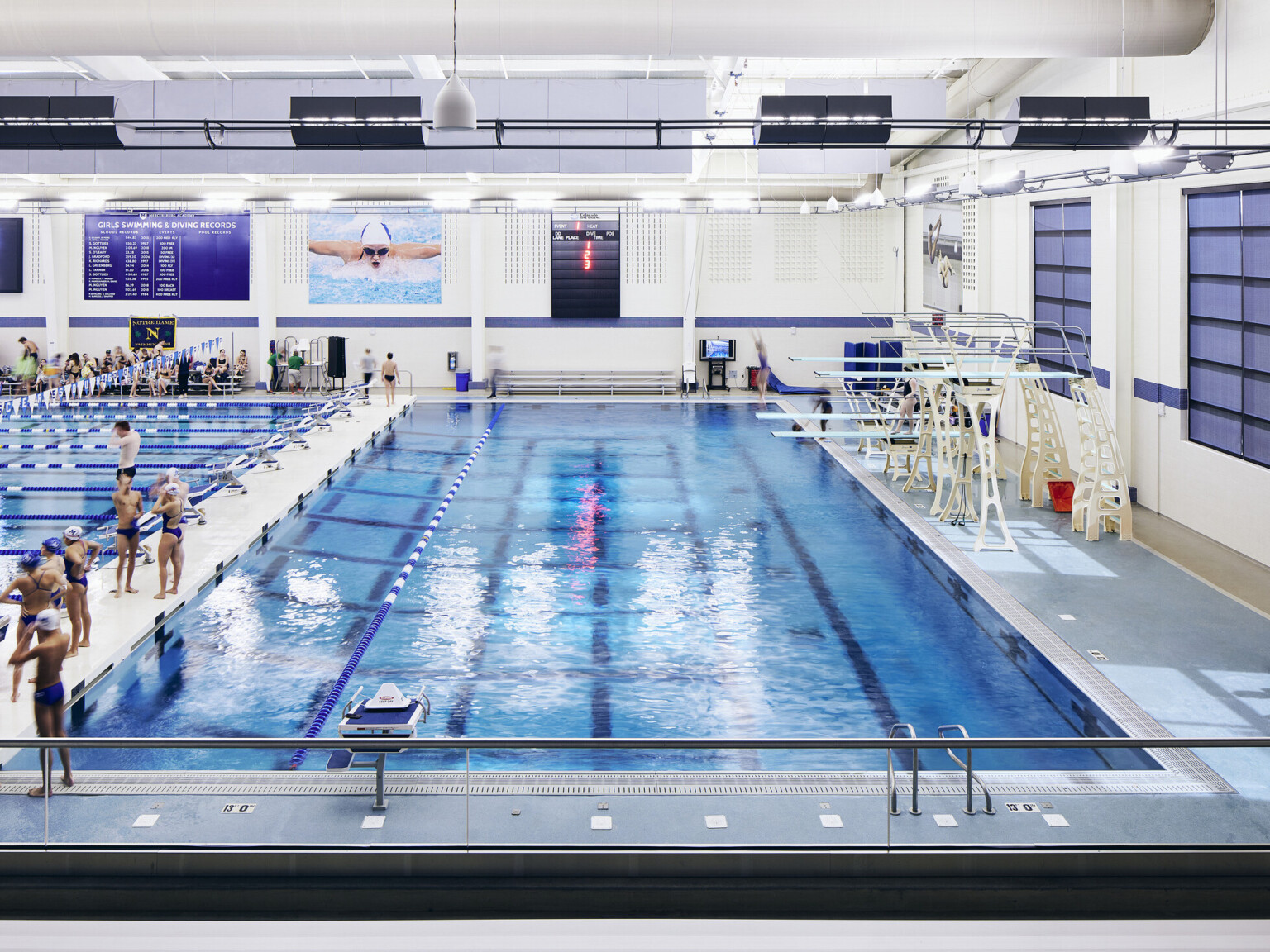 Indoor swimming pool with diving boards and swimmers engaging in conversation