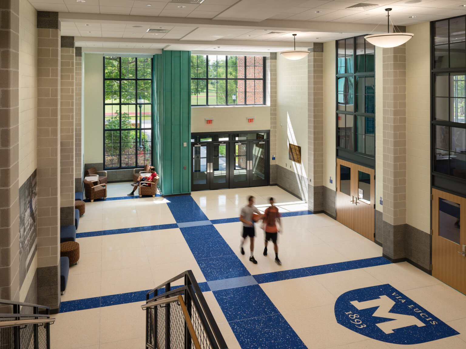 Entryway to a building looking down from the second story onto white floors with blue accents