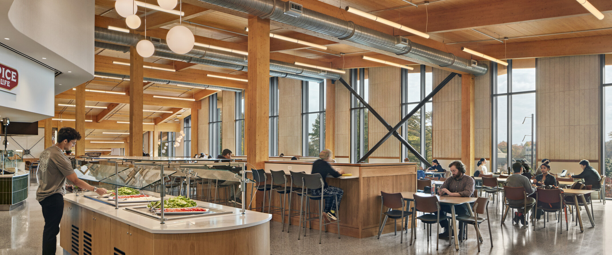 Dining area with flexible seating below wood ceiling with beam details, hanging rod lights, fireplace with white chimney back