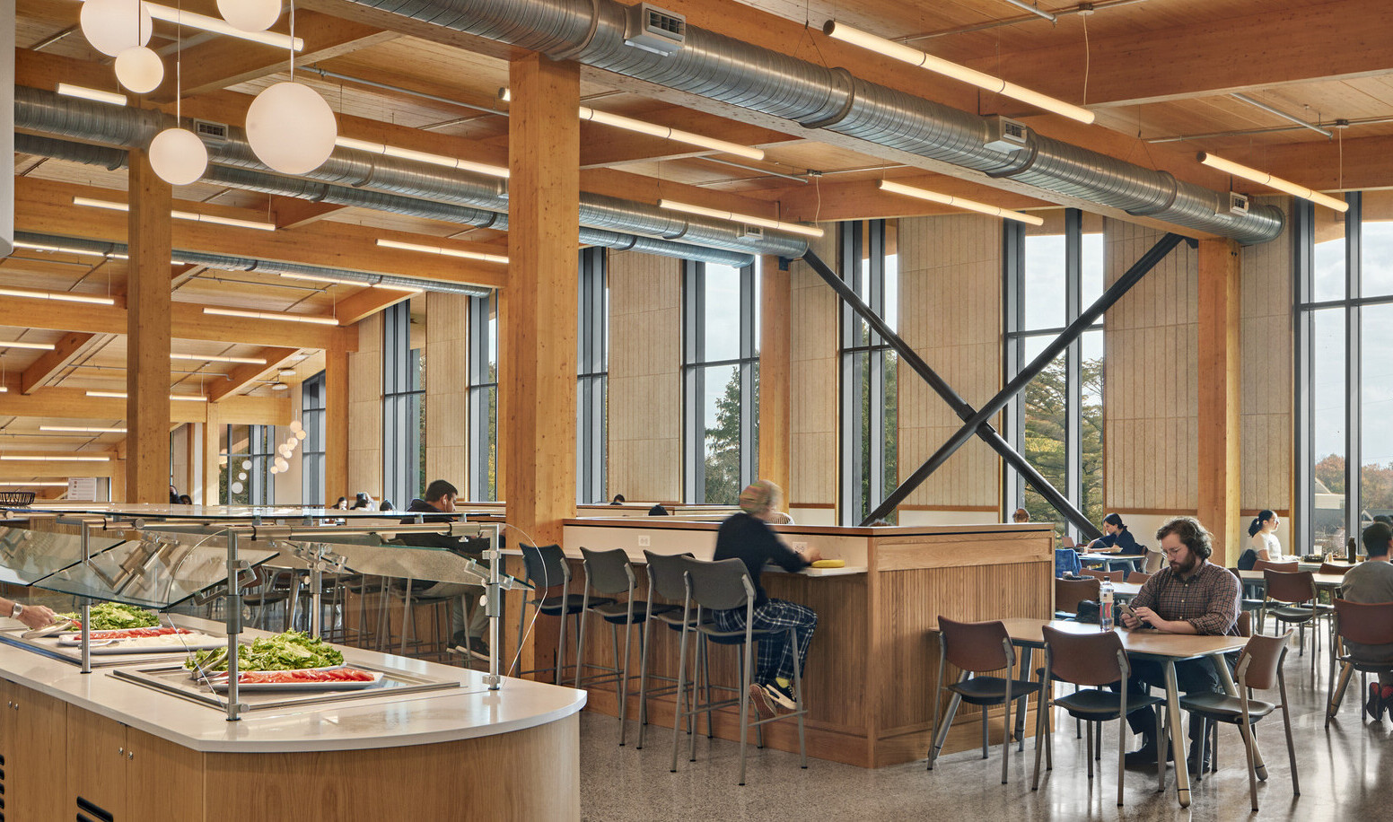 Dining area with flexible seating below wood ceiling with beam details, hanging rod lights, fireplace with white chimney back