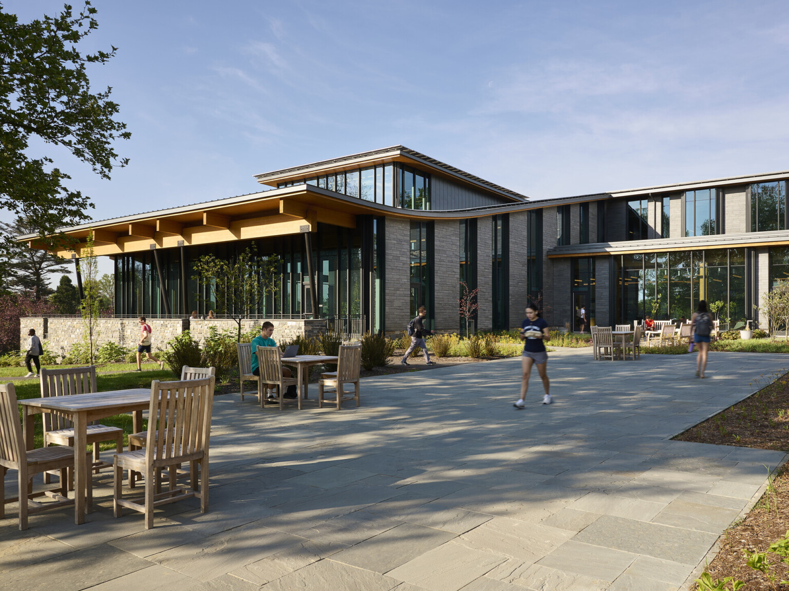 Stone and glass facade on university building with curving roof and overhang, mass timber architecture