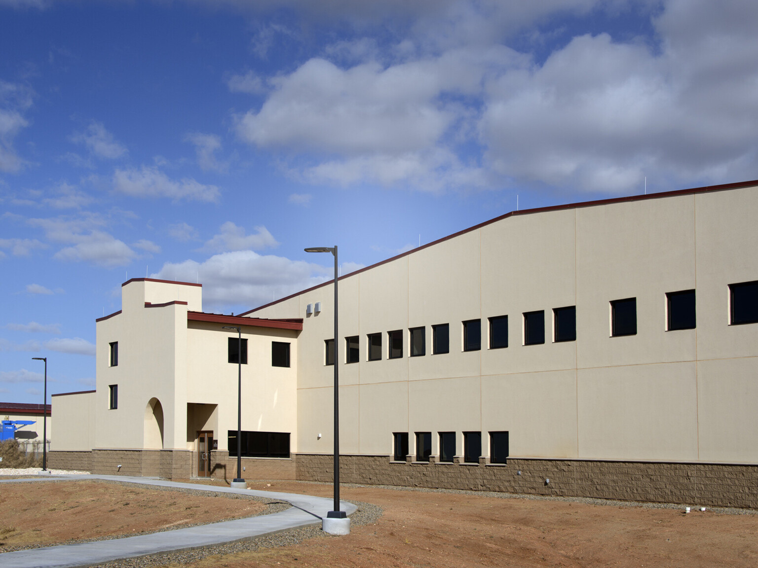 The Cannon Air Force Base Squadron Operations Facility uses mission-style architecture to meld seamlessly with the surrounding high plains of eastern New Mexico, outdoor lighting, common walkway