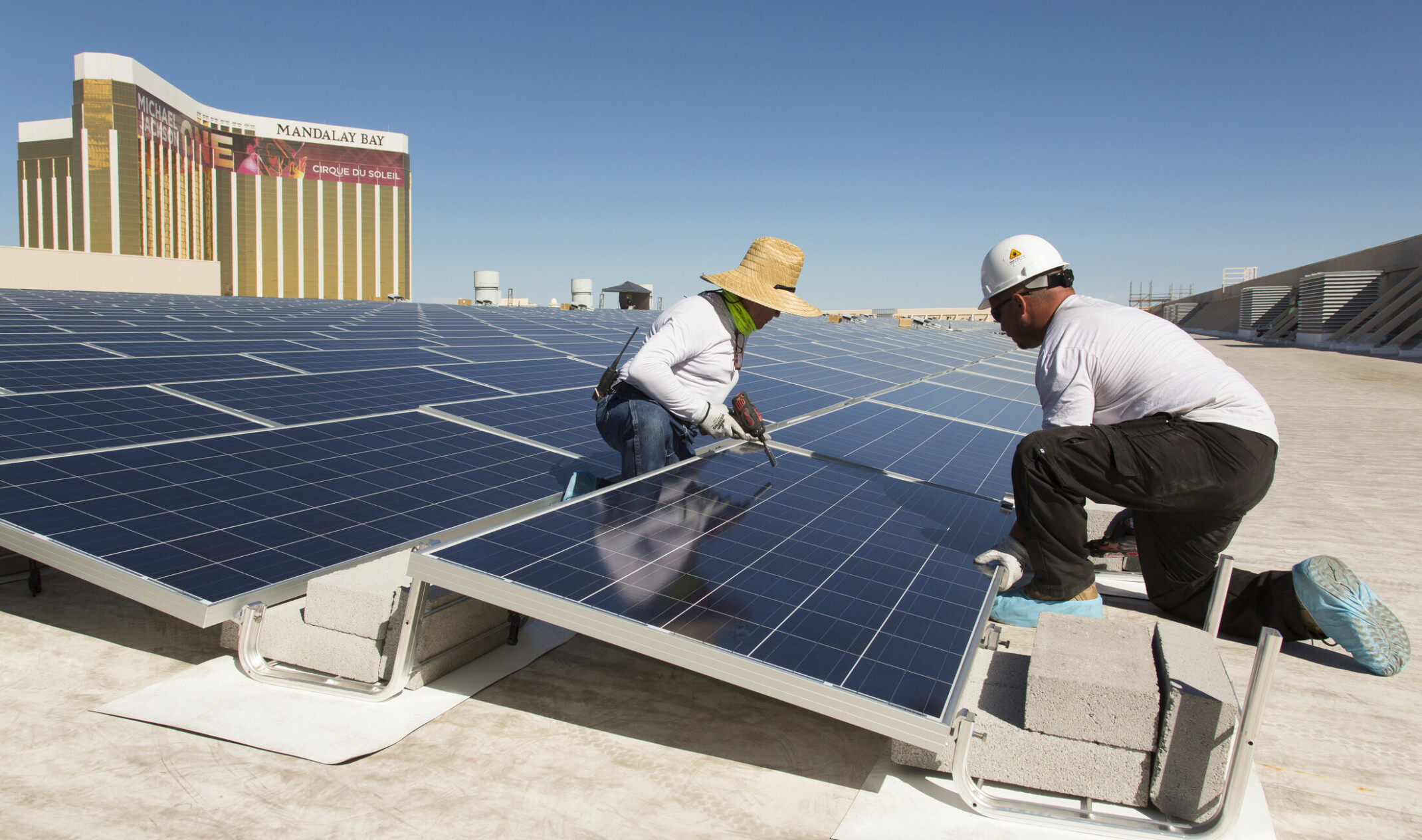 two individuals working on a solar panel; sustainable design at MGM Mandalay Bay solar array in Las Vegas