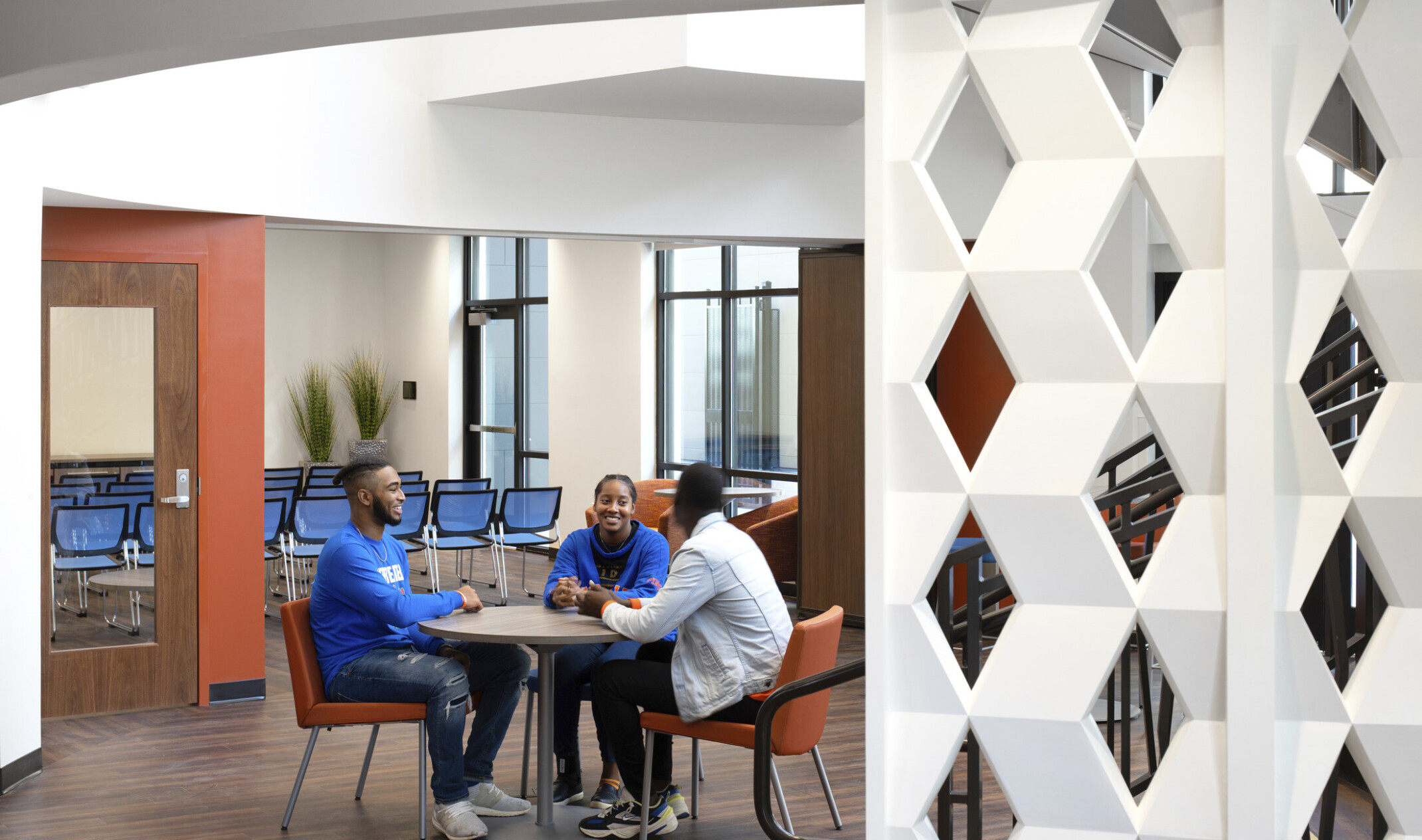 Seating area in lobby framed by white geometric panel of woven zigzags