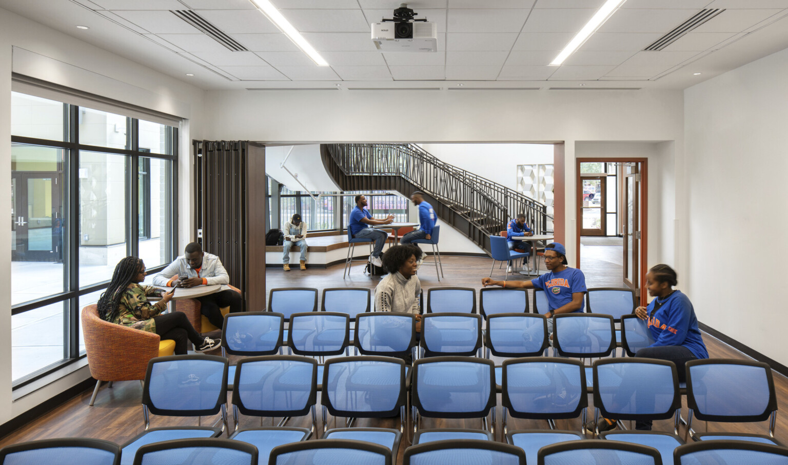 Off the main lobby with high tables and chairs, a room with flexible wall and chairs facing forward. More seats near windows