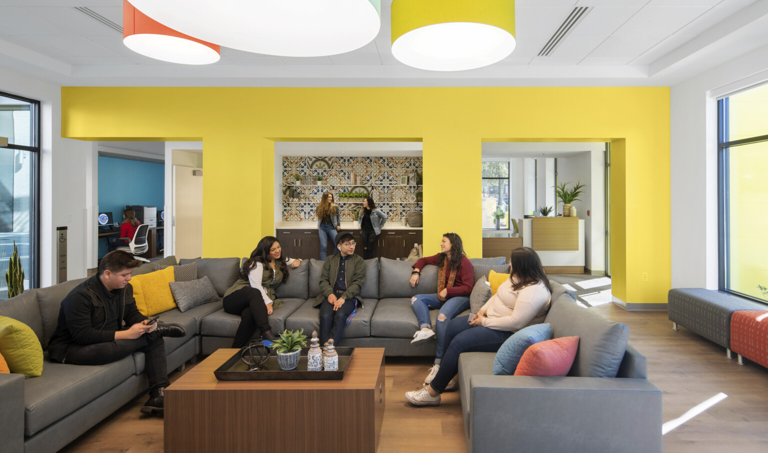 Yellow seating area off entry with large U shaped sectional and coffee table. Recessed counter in center of wall with tiles