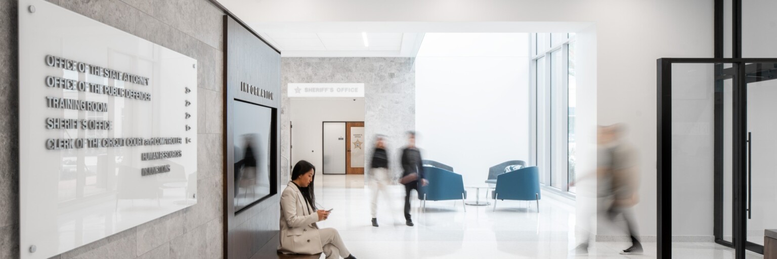 lobby at the Seminole County Justice Center Annex; woman sitting on a wooden bench, modern environment, bright and welcoming space with high ceilings