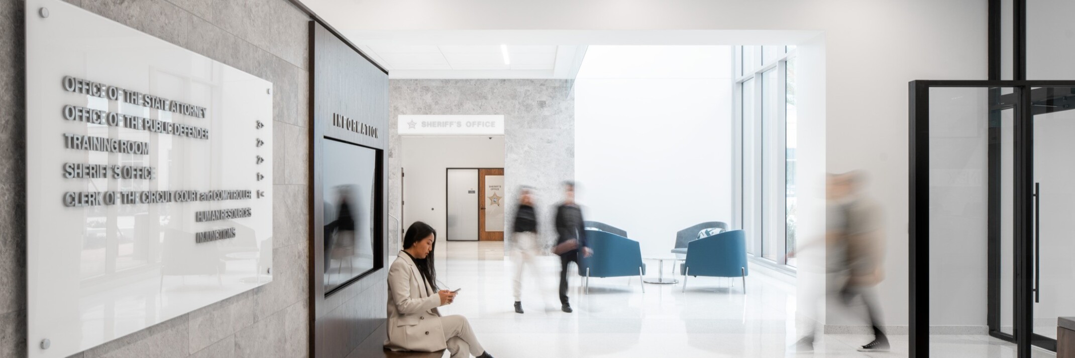lobby at the Seminole County Justice Center Annex; woman sitting on a wooden bench, modern environment, bright and welcoming space with high ceilings