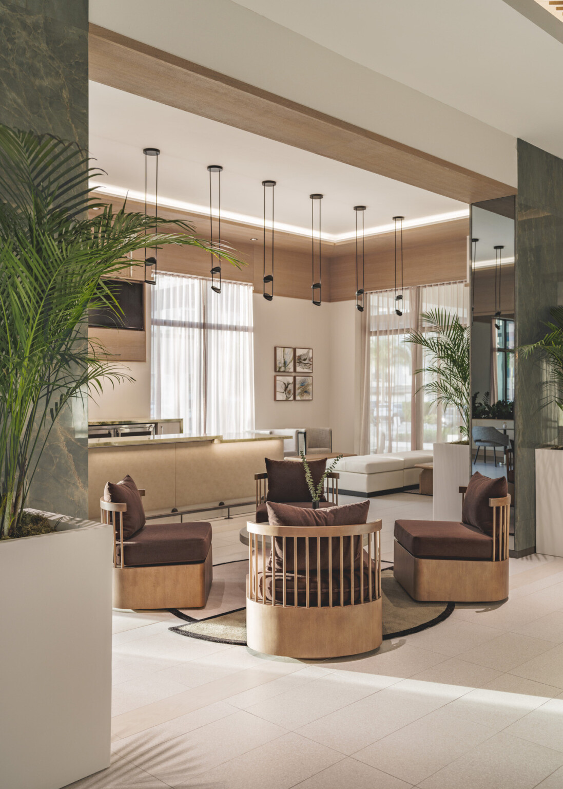 Modern hotel lobby with natural wood chairs with brown throw pillows in front of a bar area