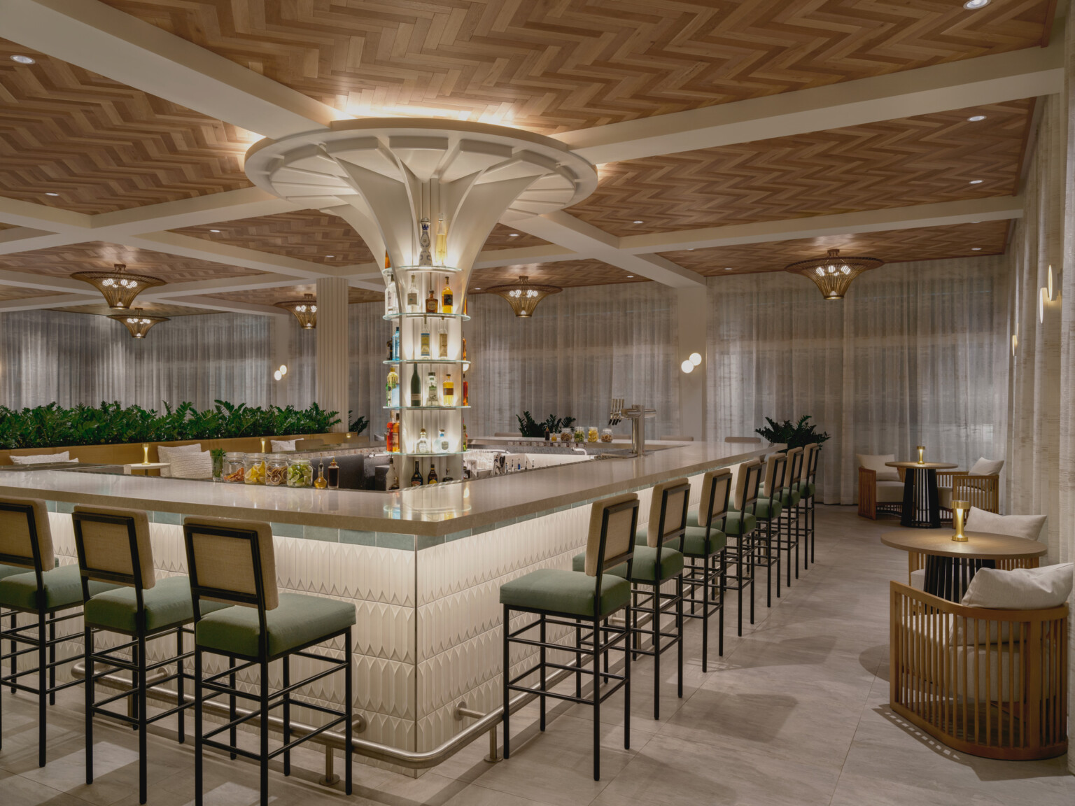 Elegant hotel bar with wooden chevron ceiling, white beams, uplighting, and bar stools with green cushions