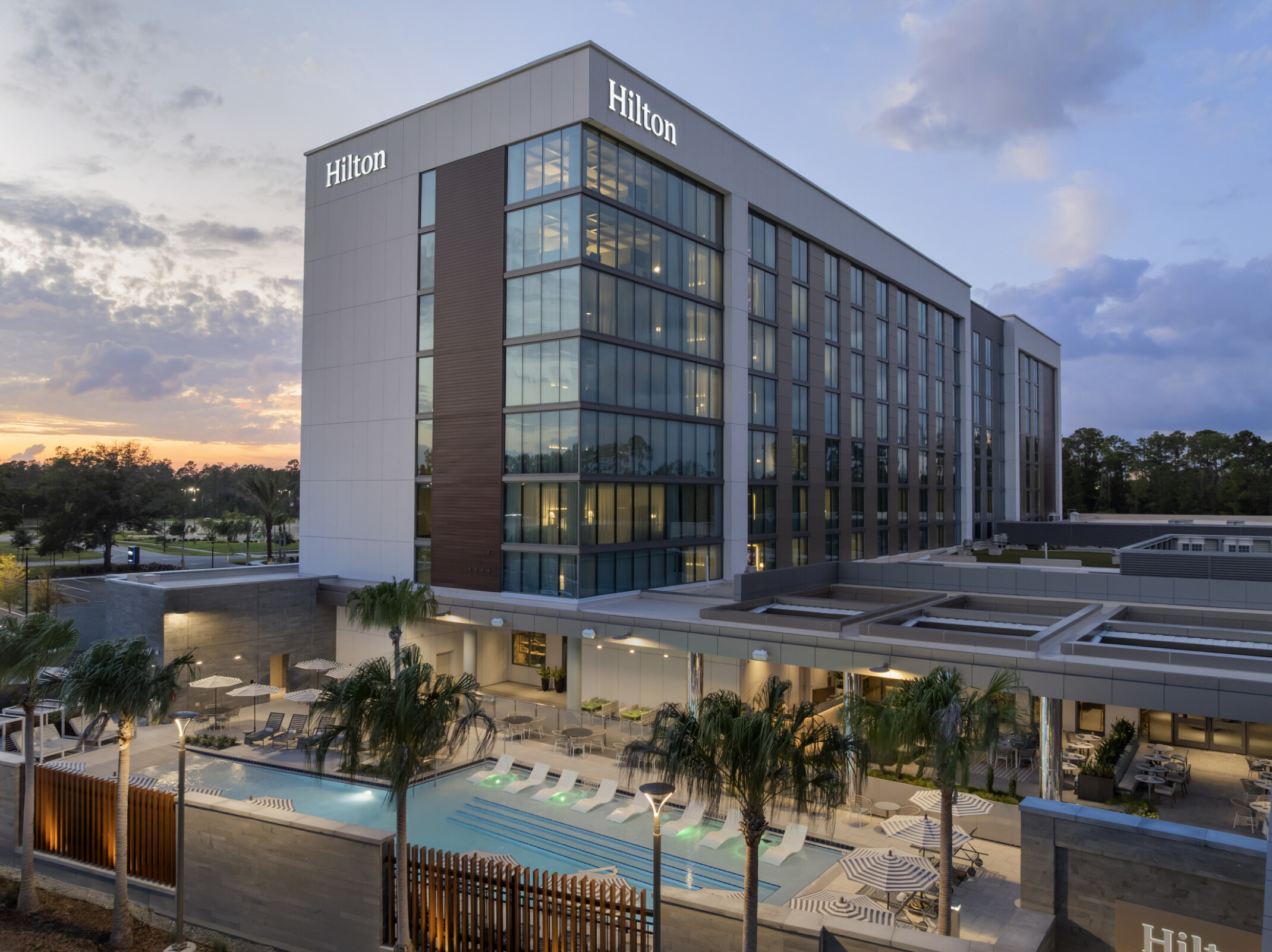Corner view of Hilton Jacksonville showcasing the resort-style pool deck and adjacent outdoor restaurant seating