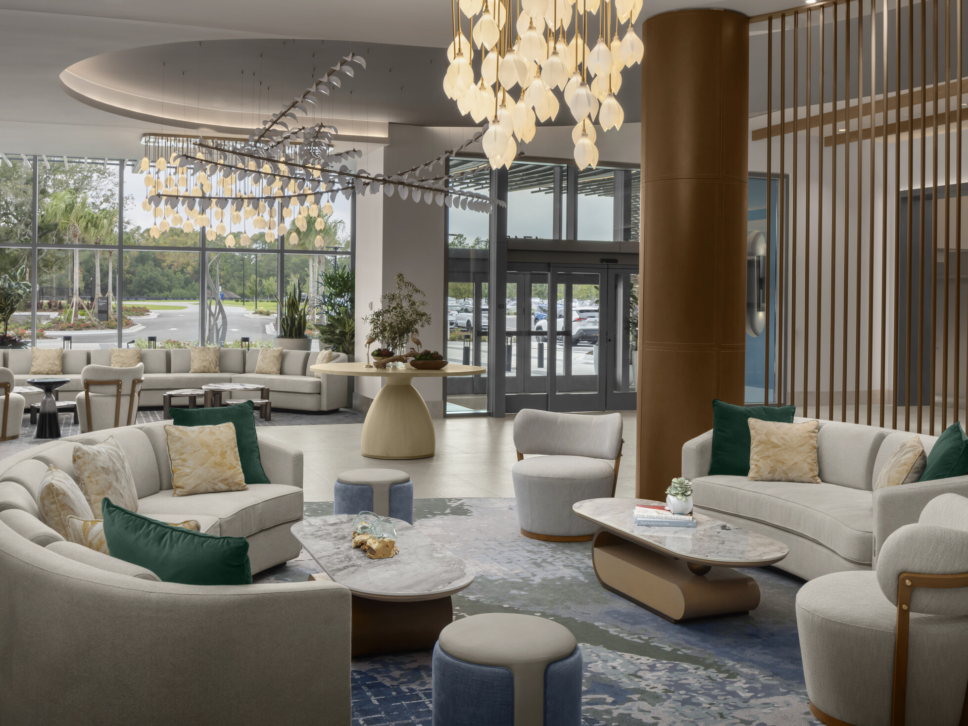 Lobby seating area at Hilton Jacksonville featuring light gray and cream furnishings with soft green accents and sculptural hanging light fixtures in a calm, coastal-inspired setting