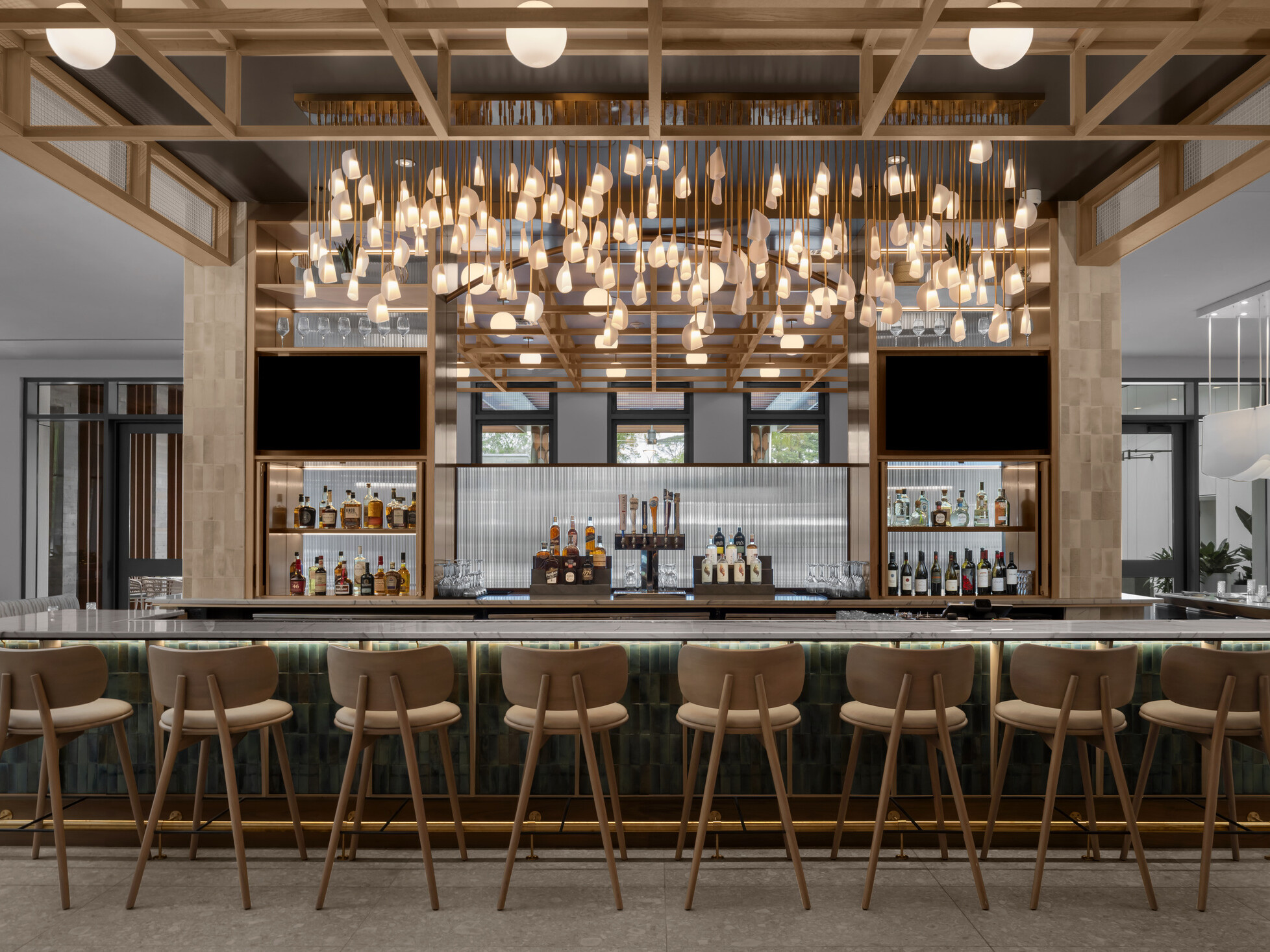 Hotel bar at Hilton Jacksonville featuring warm wood millwork, coastal-inspired detailing, and sculptural hanging light fixtures defining the space