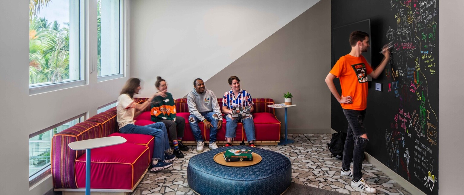 Students engaging in a classroom with colorful furniture and a blackboard wall