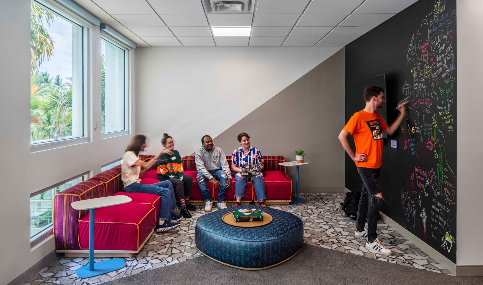 Students engaging in a classroom with colorful furniture and a blackboard wall