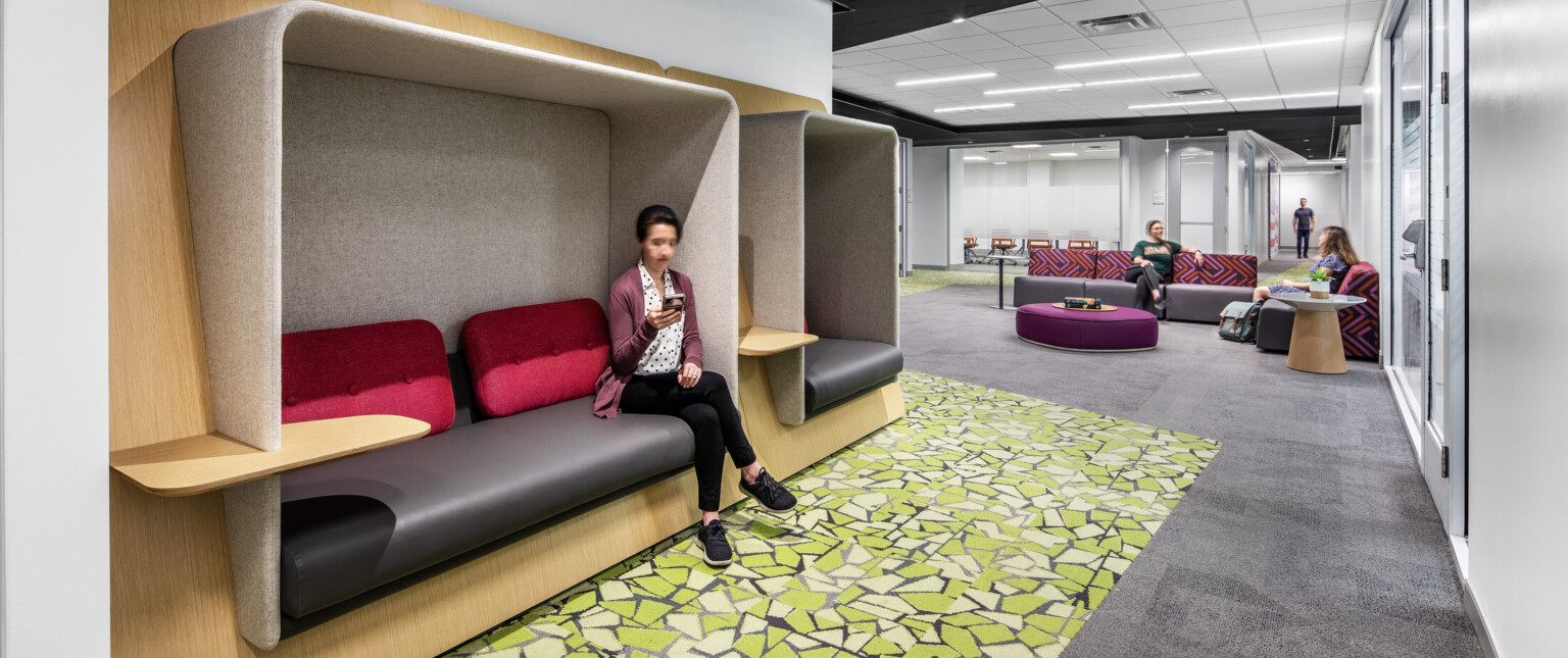 Lounge area with colorful seating areas, green carpeting, and light wood accents