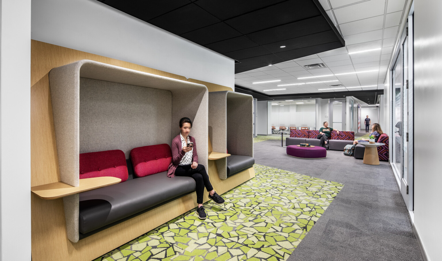 Lounge area with colorful seating areas, green carpeting, and light wood accents