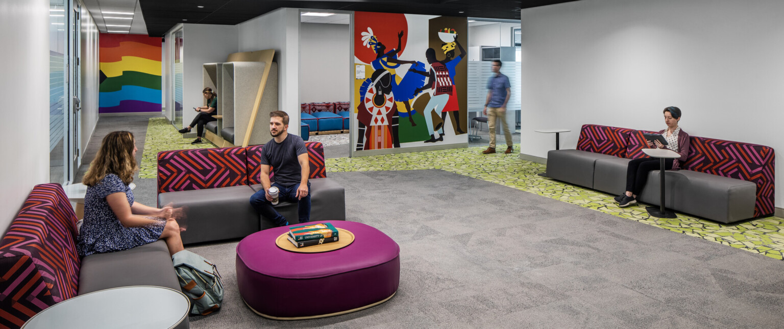 Lounge area with colorful seating areas and vibrant wall murals filled with students