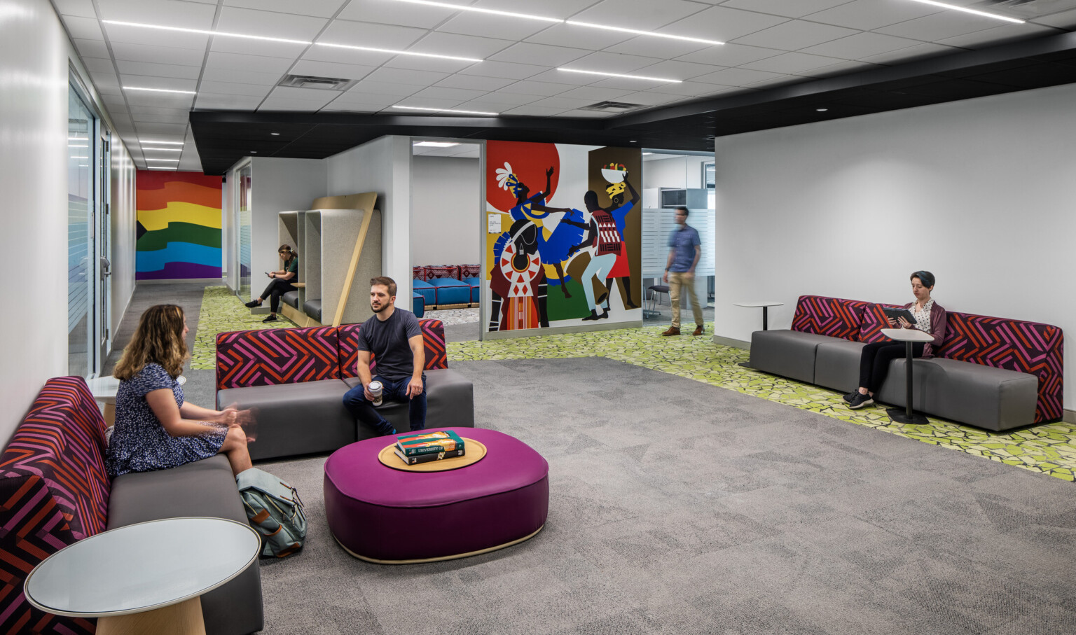 Lounge area with colorful seating areas and vibrant wall murals filled with students
