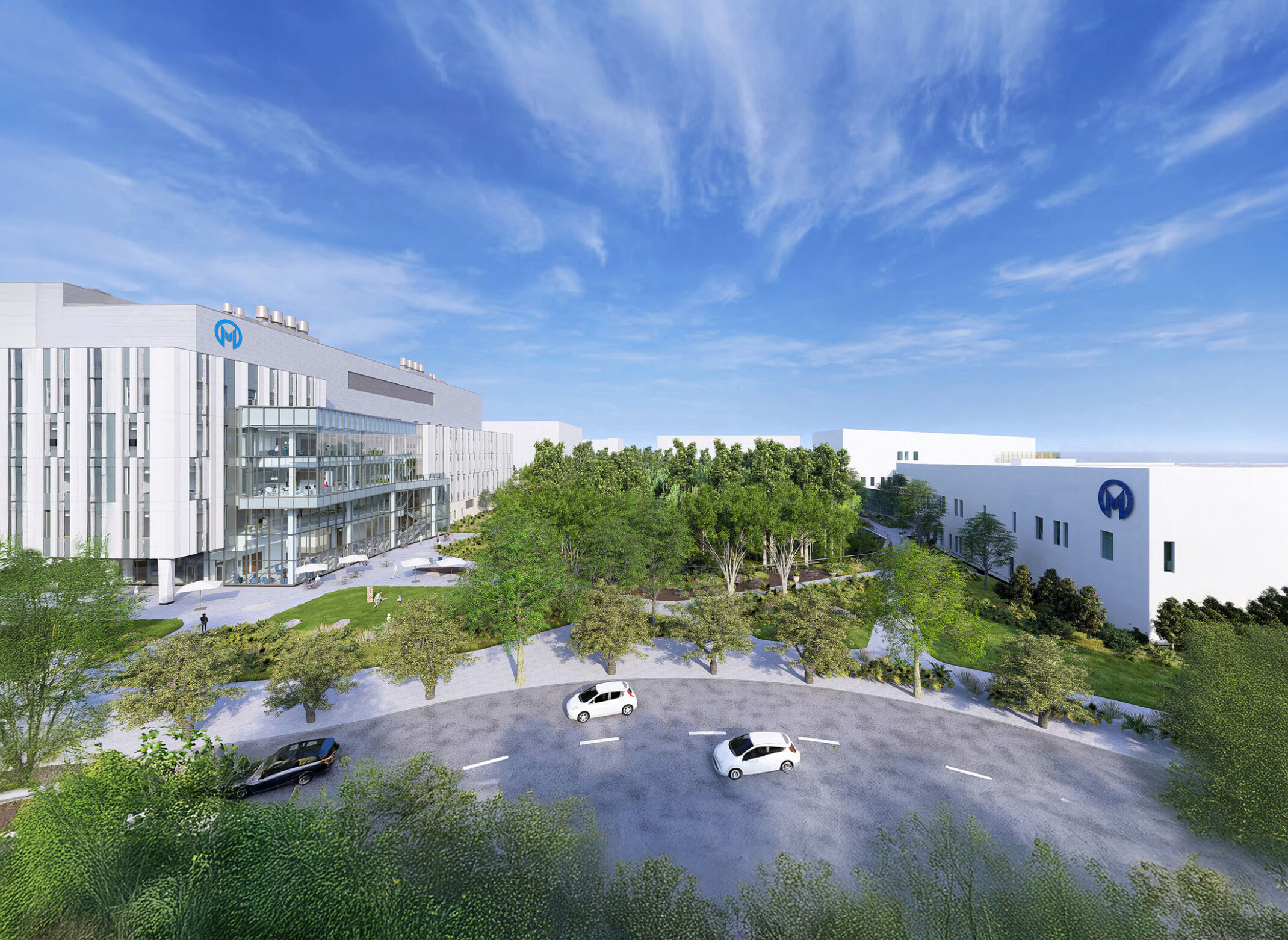 A modern medical campus with two large buildings separated by a green area with trees.