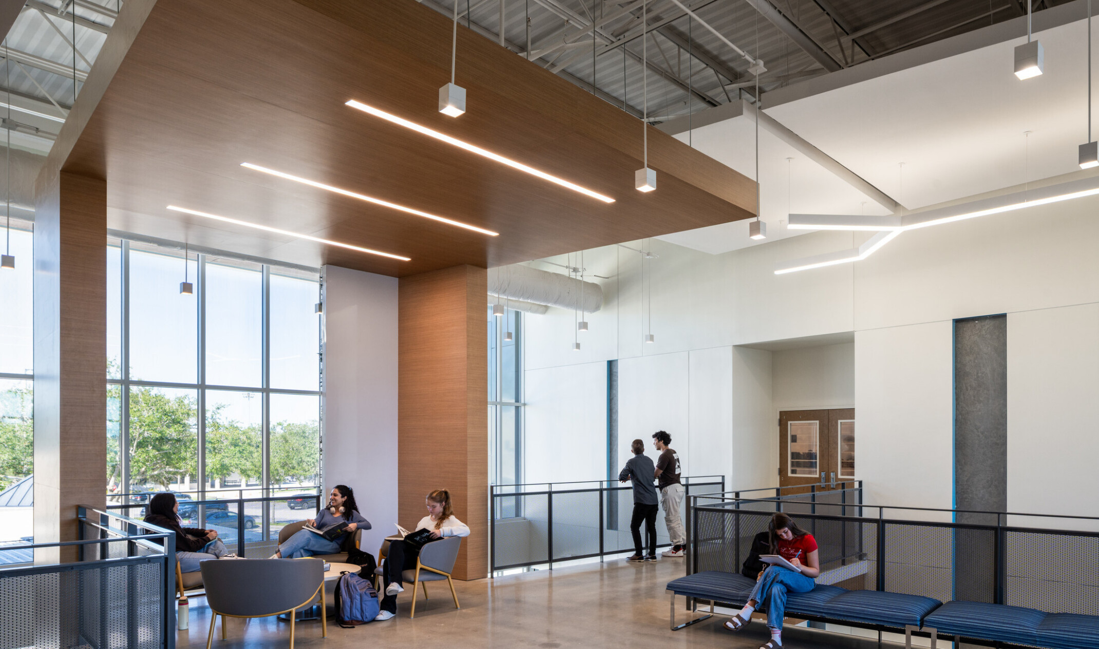 School hallway and common area; open circulation for social interactions; tables and benches for quiet study; whole-wall windows for natural light