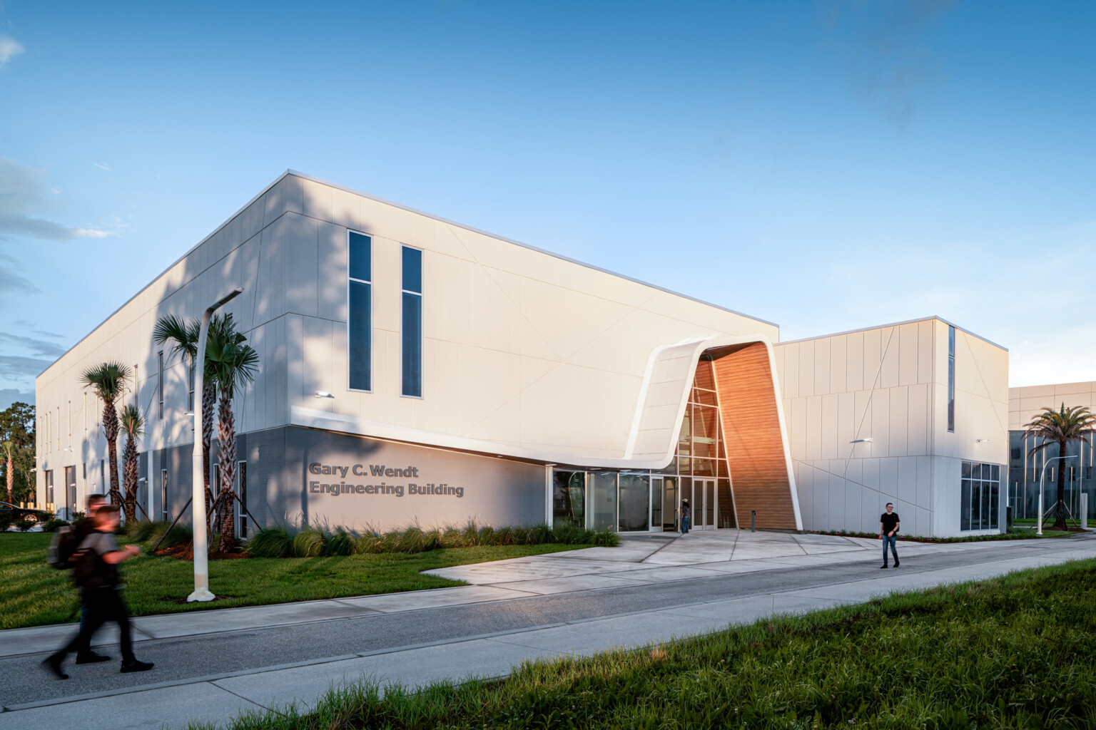 A modern white building featuring tall vertical windows and an angled entrance.
