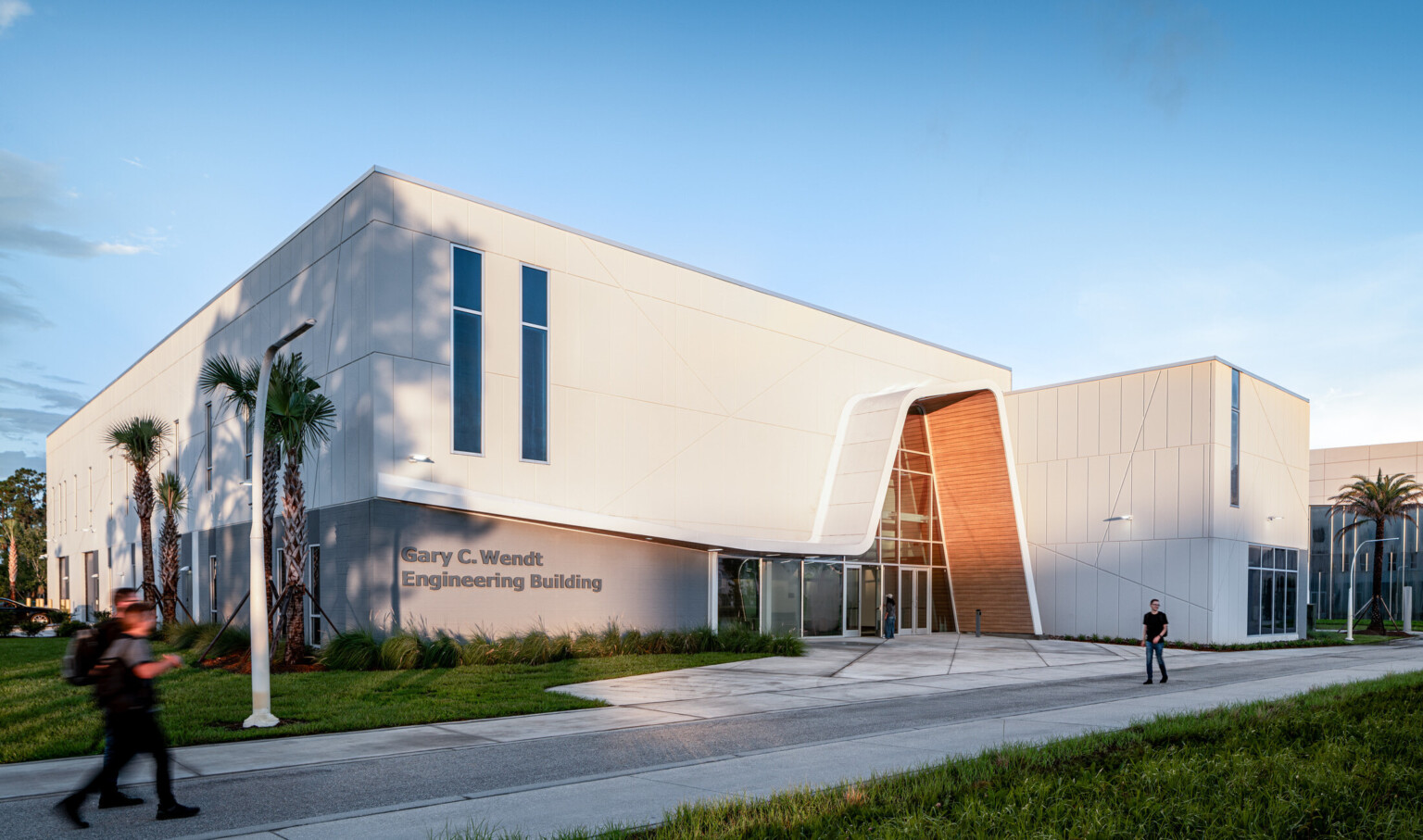 A modern white building featuring tall vertical windows and an angled entrance.