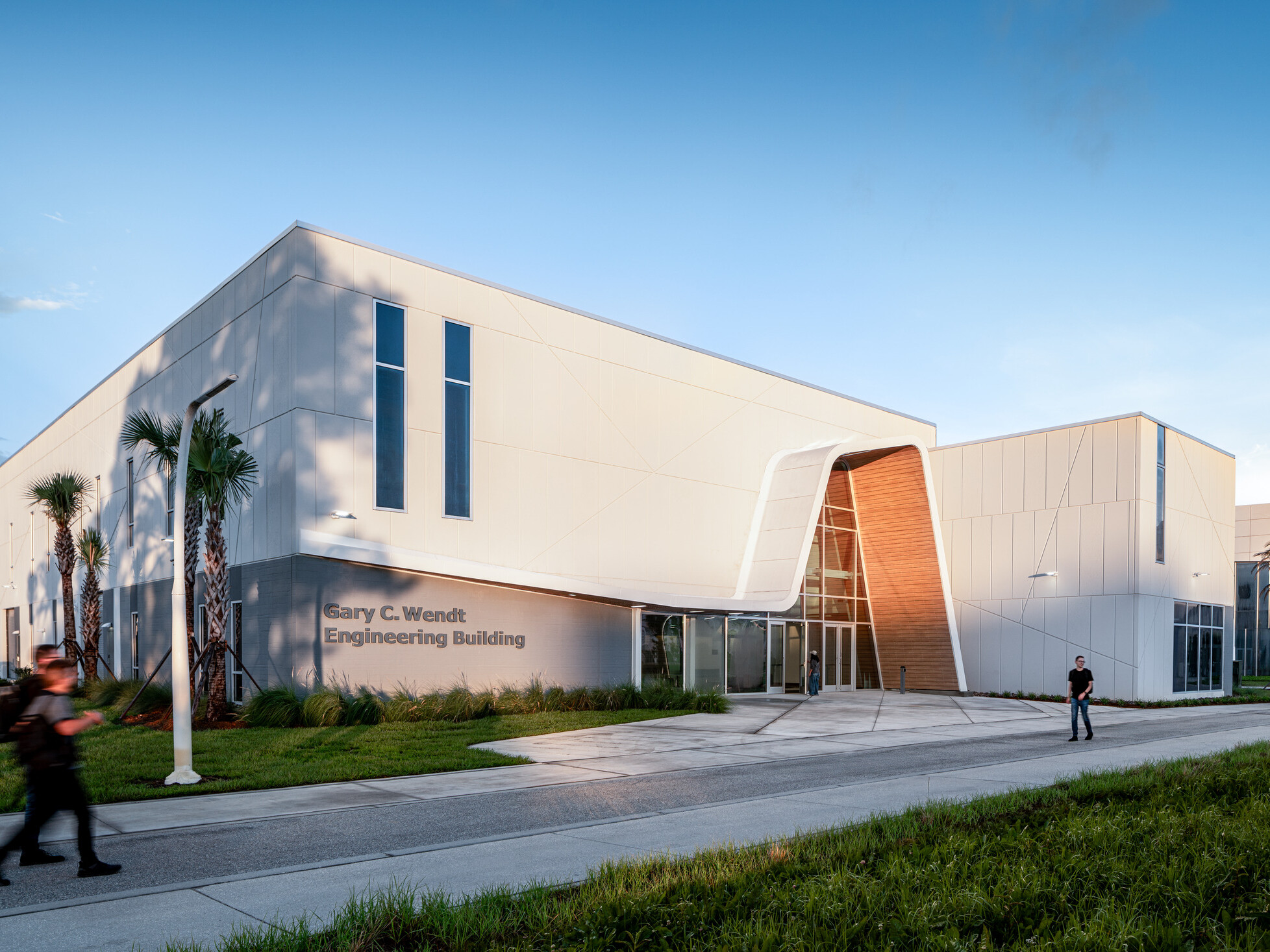 A modern white building featuring tall vertical windows and an angled entrance.
