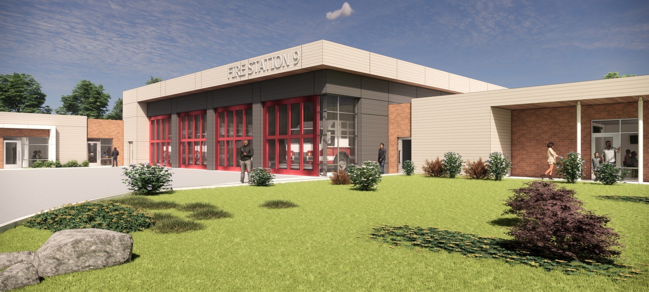 Front view of fire station with four engine bays and a light brick façade. In the foreground, a landscaped lawn.