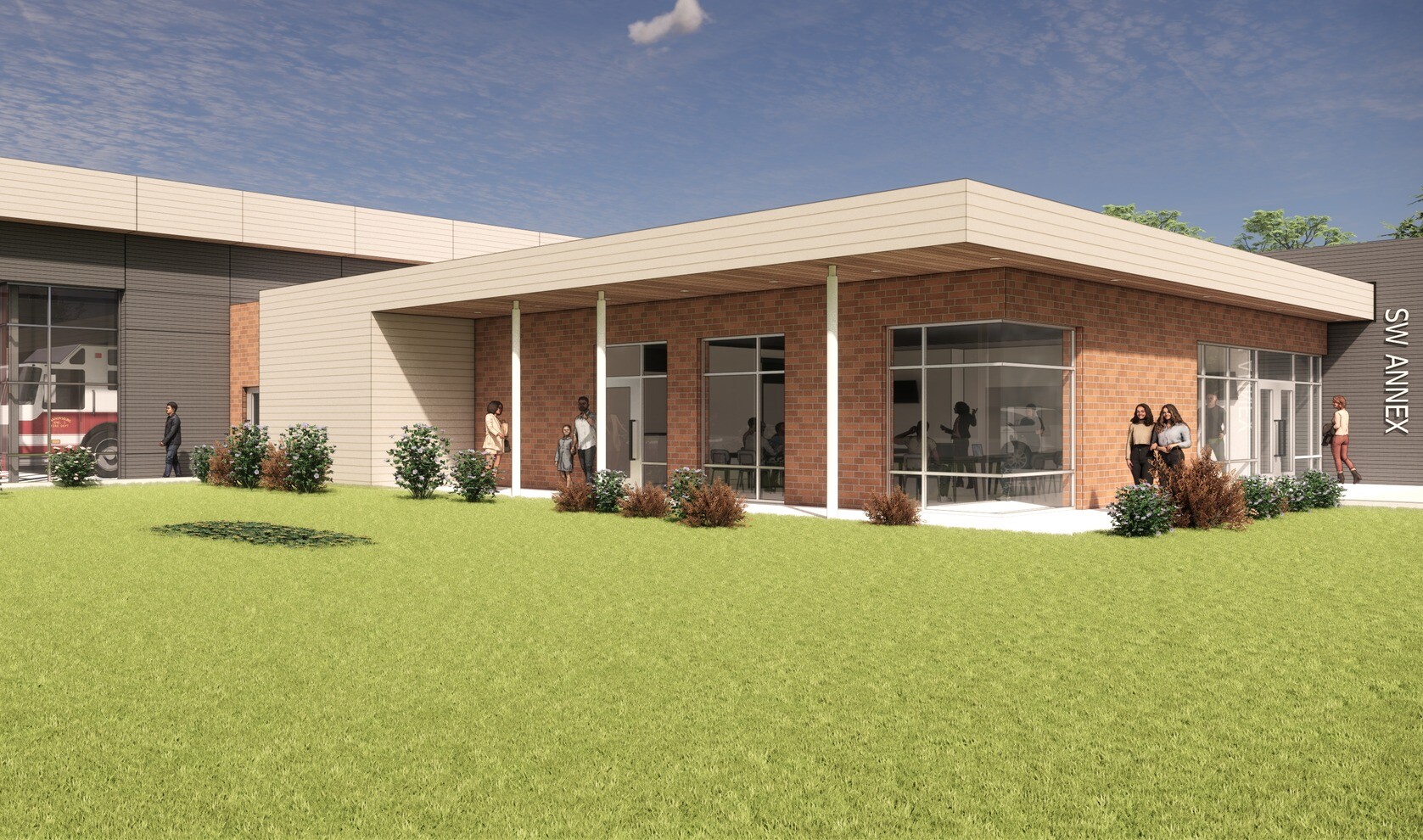 Corner view of the Public Safety Annex. Large windows look into a community gathering space with a lawn in the foreground.