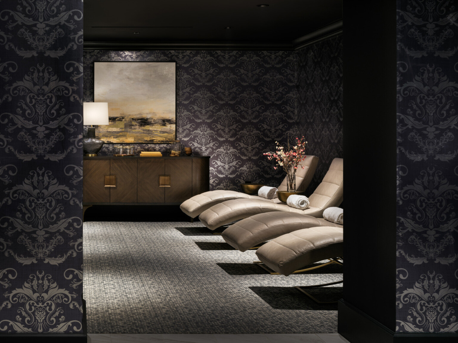 Luxurious spa area with black and silver wallpaper, gold lounge chairs, with bronze furnishings