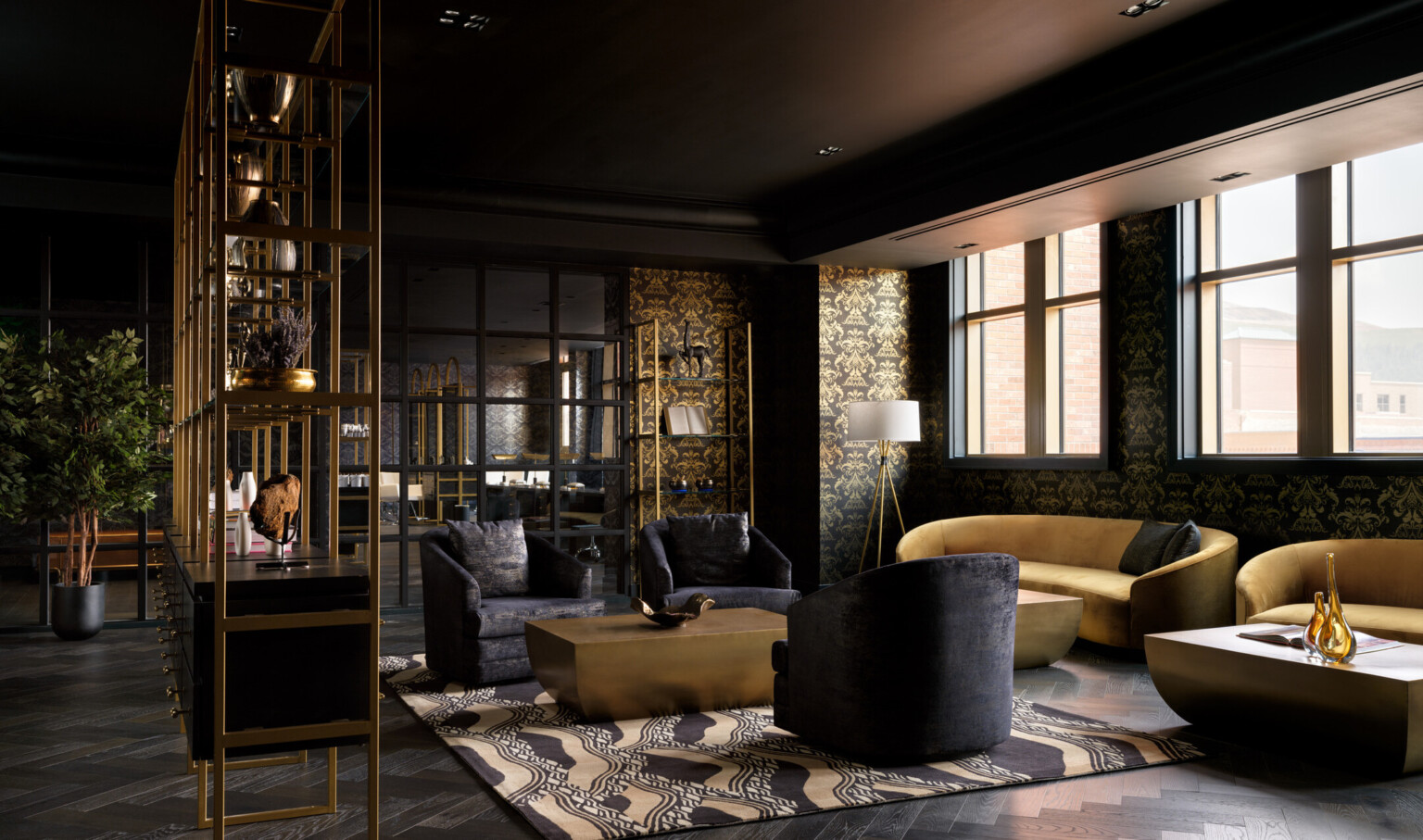 Dramatic seating area with black wallpaper filled with designs in gold, gold couches, black chairs, black and gold shelves Dramatic seating area with black wallpaper filled with designs in gold, gold couches, black chairs, black and gold shelves