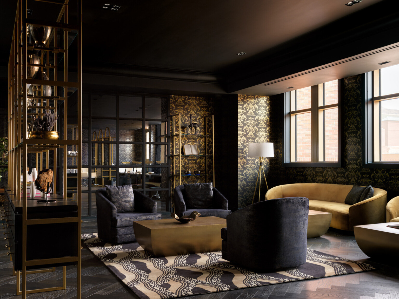 Dramatic seating area with black wallpaper filled with designs in gold, gold couches, black chairs, black and gold shelves Dramatic seating area with black wallpaper filled with designs in gold, gold couches, black chairs, black and gold shelves