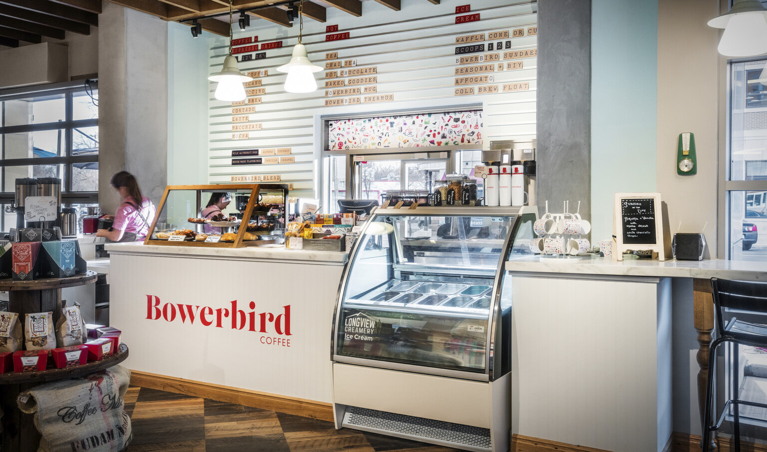 White Bowerbird Coffee counter with marble top and wood pastry display box. Between sections is a Longview Creamery cooler