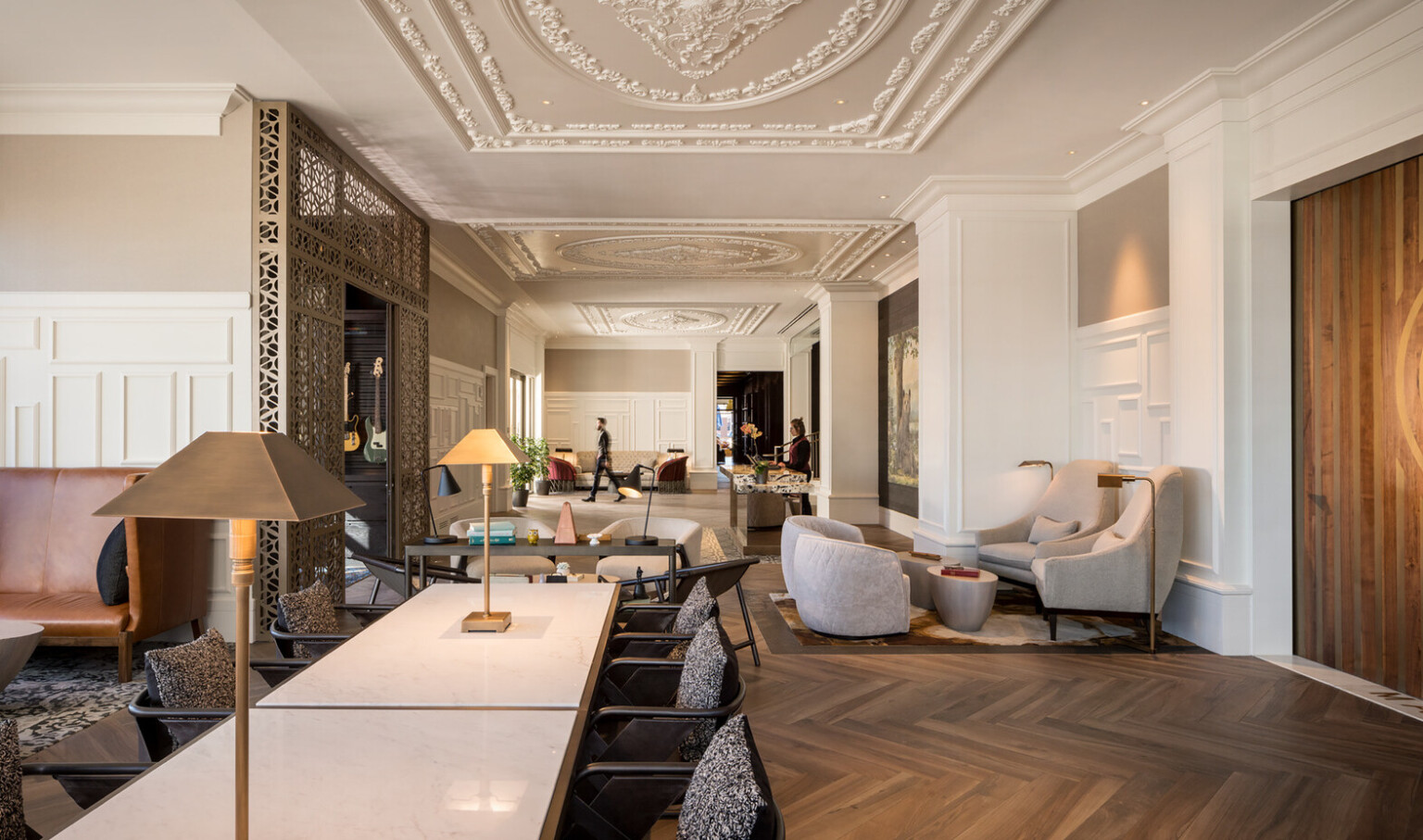 White lobby hallway with beige accents and ornate organic decorative molding on ceilings with recessed lights