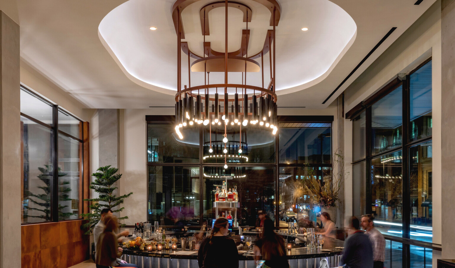 Interior of the same lounge space. Round bar at center, shape mirrored with recessed ceiling and elaborate modern chandelier