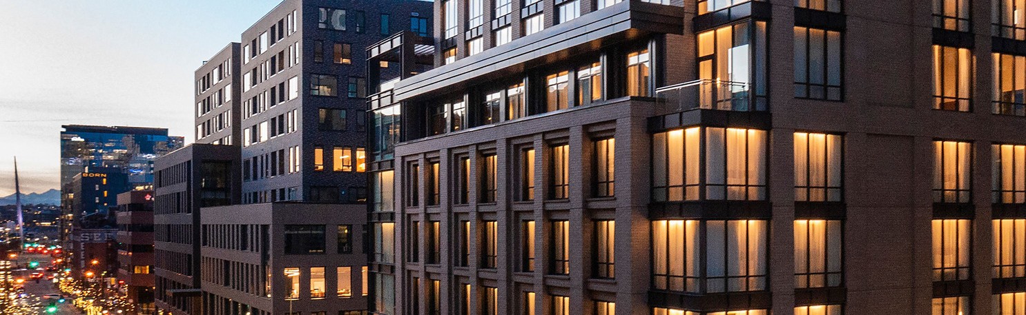 Denver hotel view at night, warm brick facade lit up with golden hues