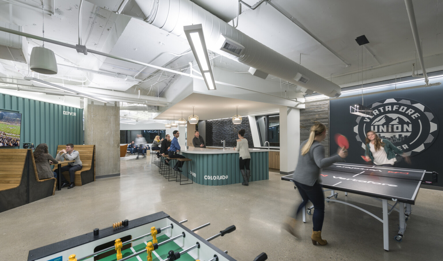 Vertafore Headquarters interior room with teal panel accents in space with counter, wood booths, and ping pong table Vertafore Headquarters interior room with teal panel accents in space with counter, wood booths, and ping pong table