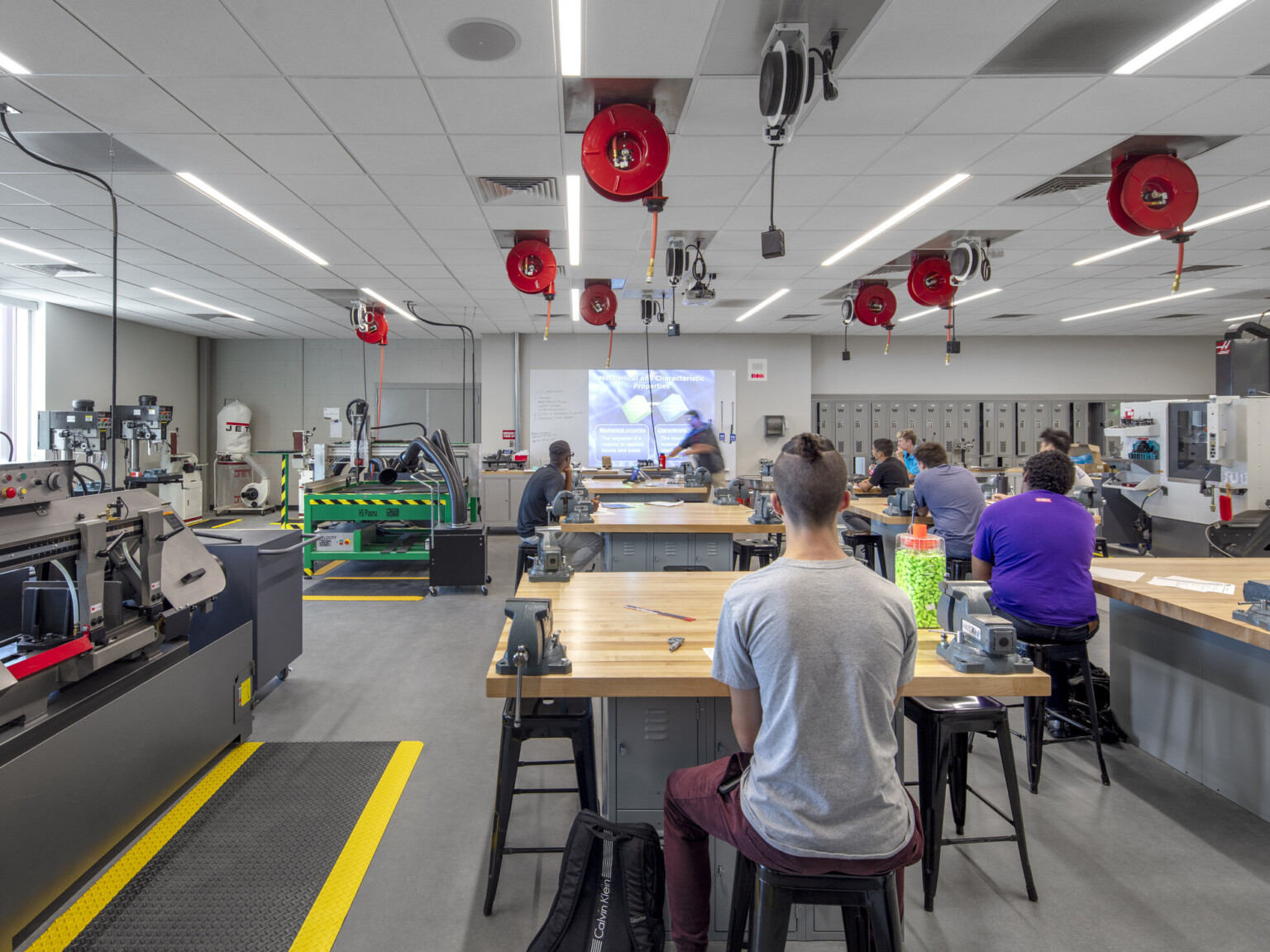 Classroom with equipment along left wall. Tables and stools in rows, right, with extension cords dispensed from above, cherry creek innovation campus, ccic cherry creek, cherry creek high school