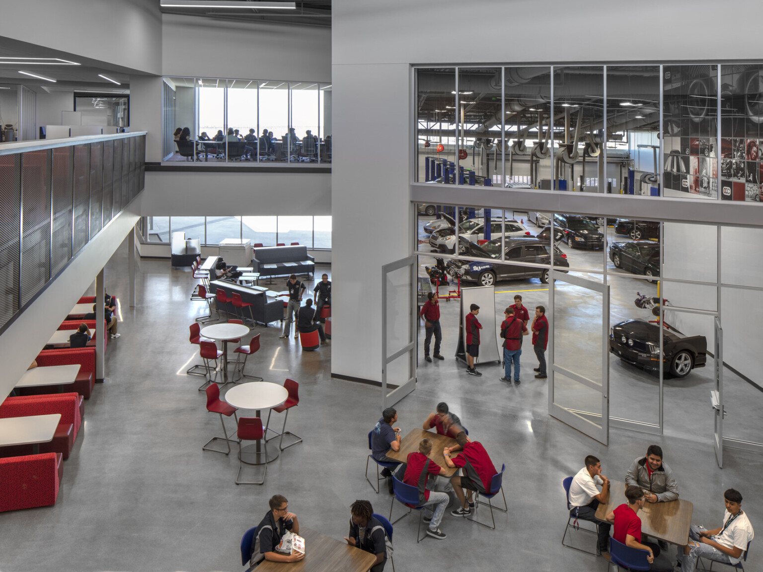 View from 2nd floor balcony overlooking seating and glass entrance to double height auto industry and mechanic specific lab, cherry creek innovation campus, ccic cherry creek, cherry creek high school