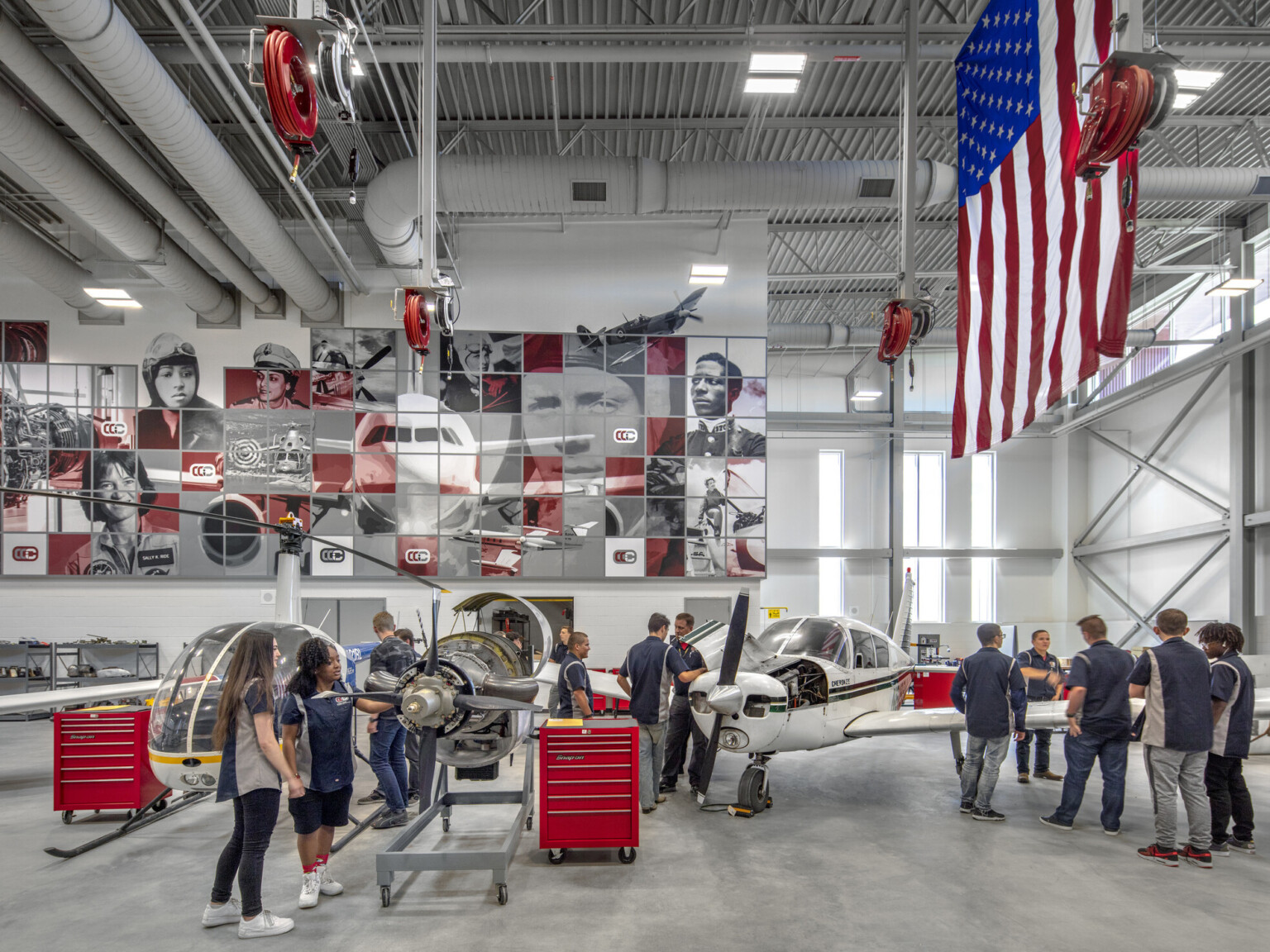 Aviation lab with helicopter, small plane, and displayed engine, mural at back with planes and pilots, american flag, right, cherry creek innovation campus, ccic cherry creek, cherry creek high school