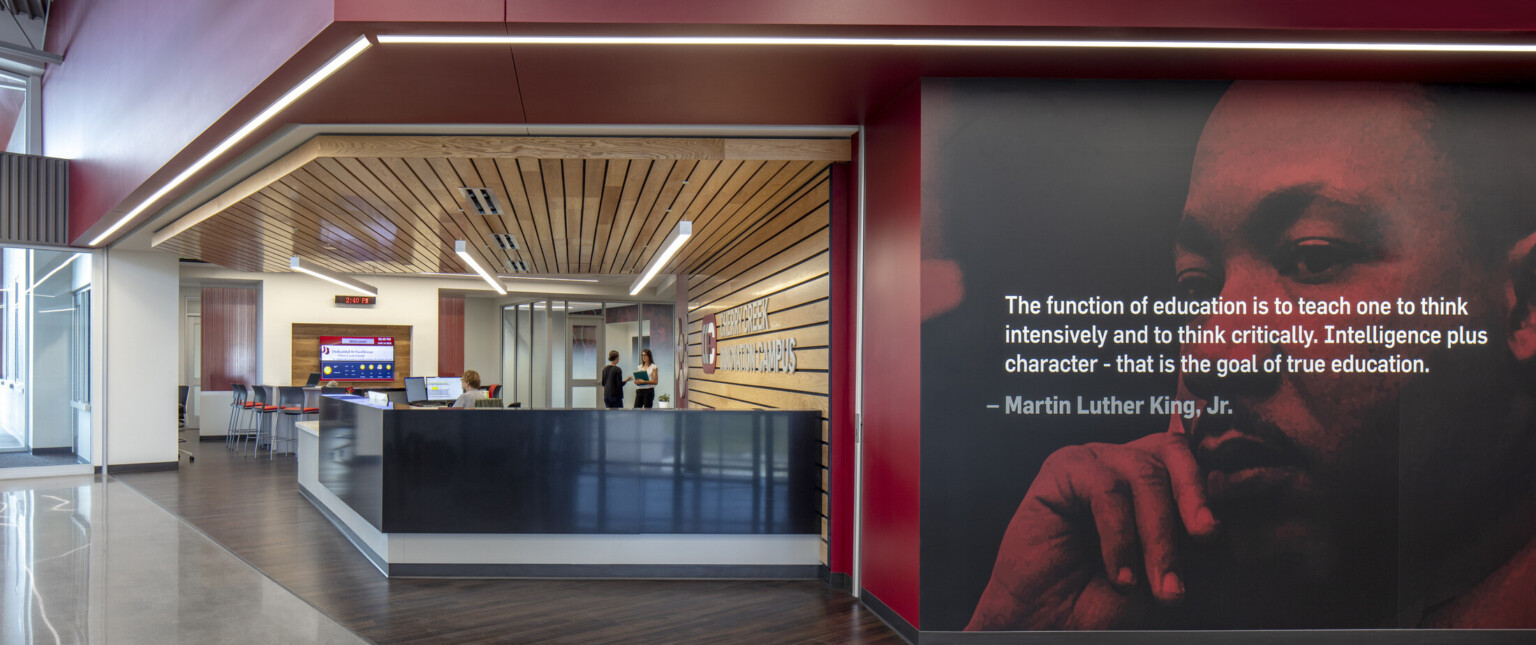 Black reception desk in wood panel recessed room off hallway with photo mural of Martin Luther King Jr. with quote overlaid