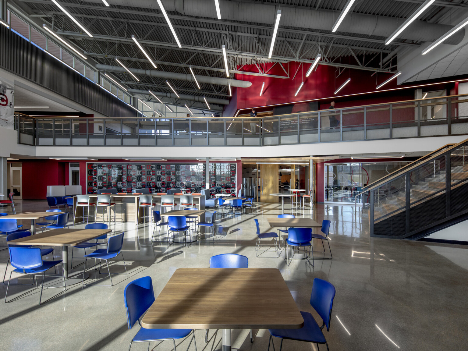 Seating area in double height room with natural lighting. 2nd floor walkway to back extends over entrance to classroom, cherry creek innovation campus, ccic cherry creek, cherry creek high school