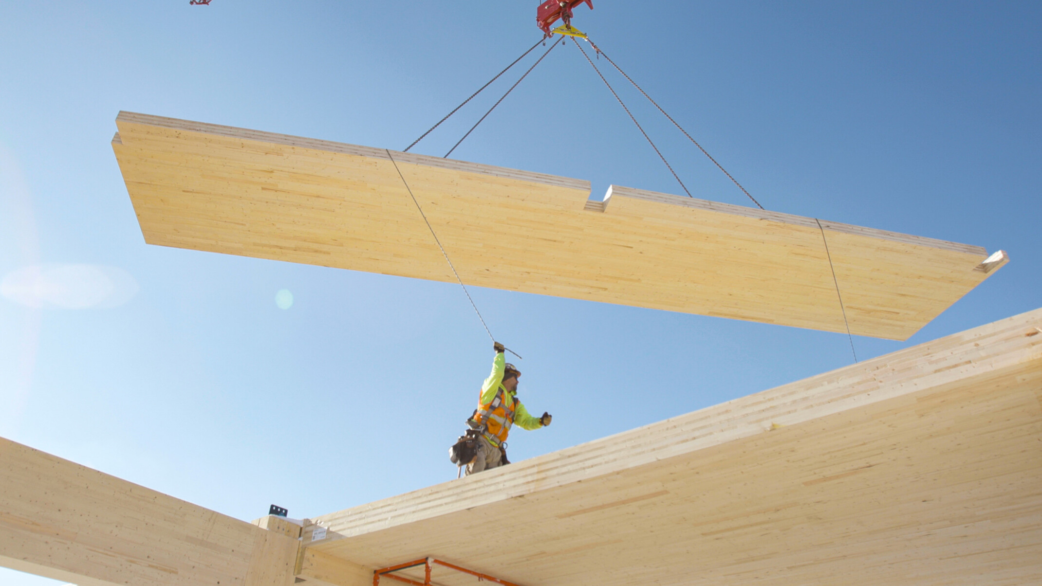 timber panel being lifted on a crane with construction worker directing