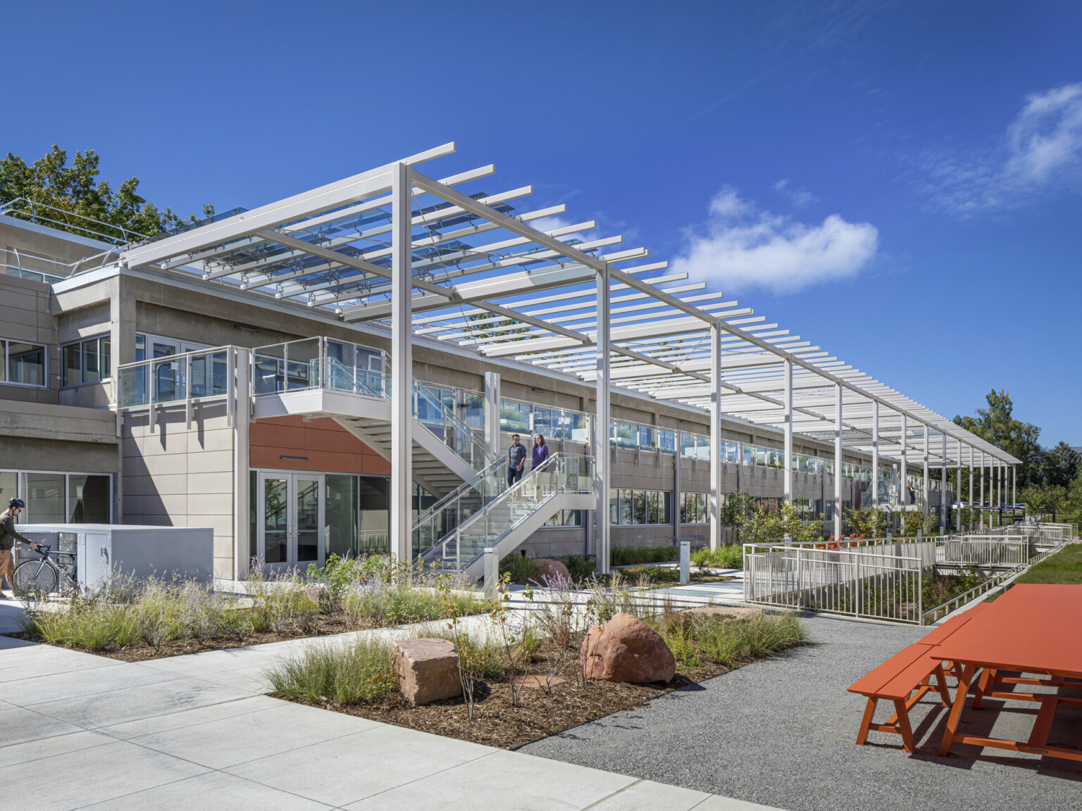 Multilevel building with white metal decorative columns and awnings with a red picnic table