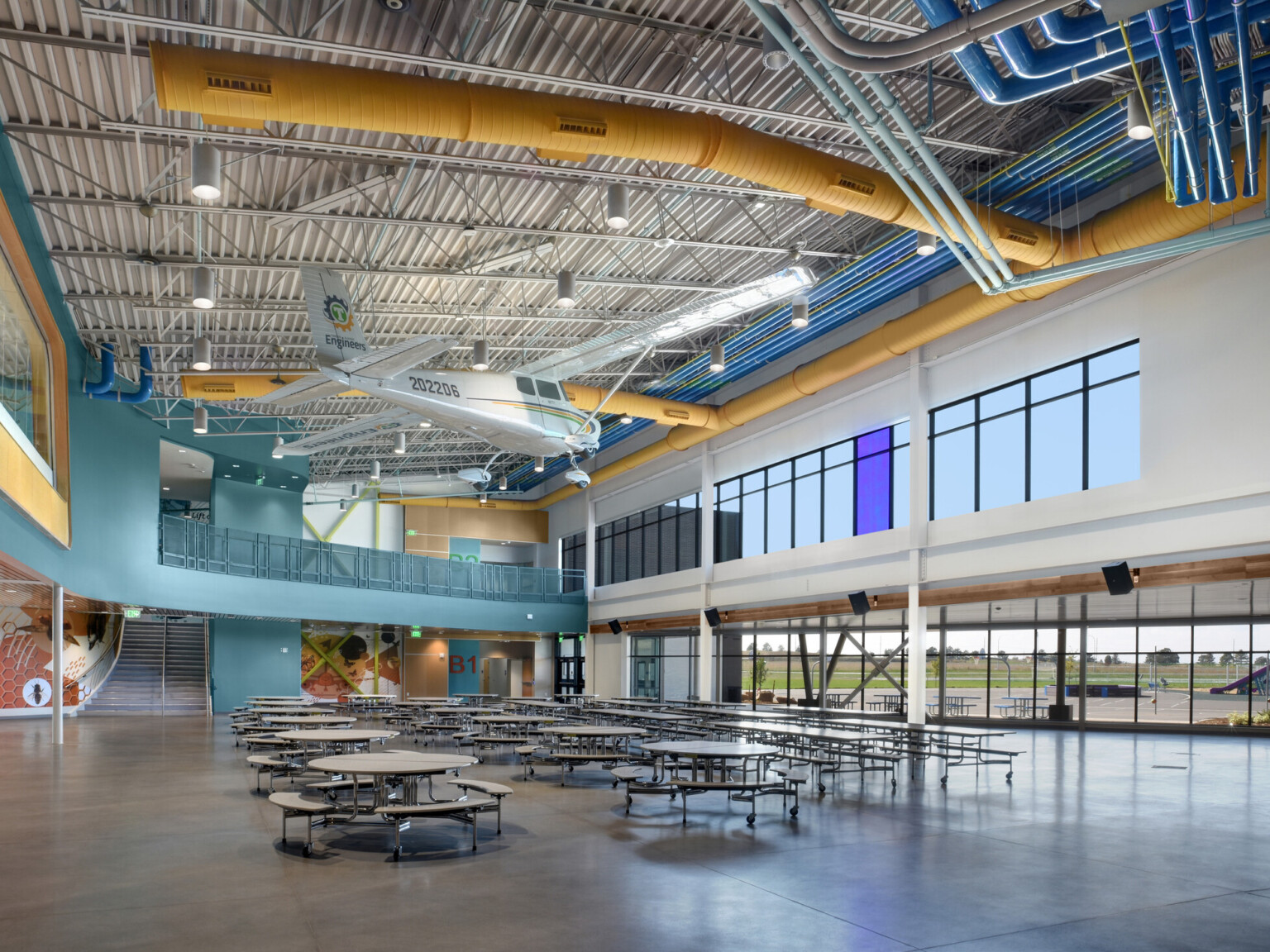 cathedral ceilings, large windows, teal blue walls, polished concrete flooring, dining tables and benches