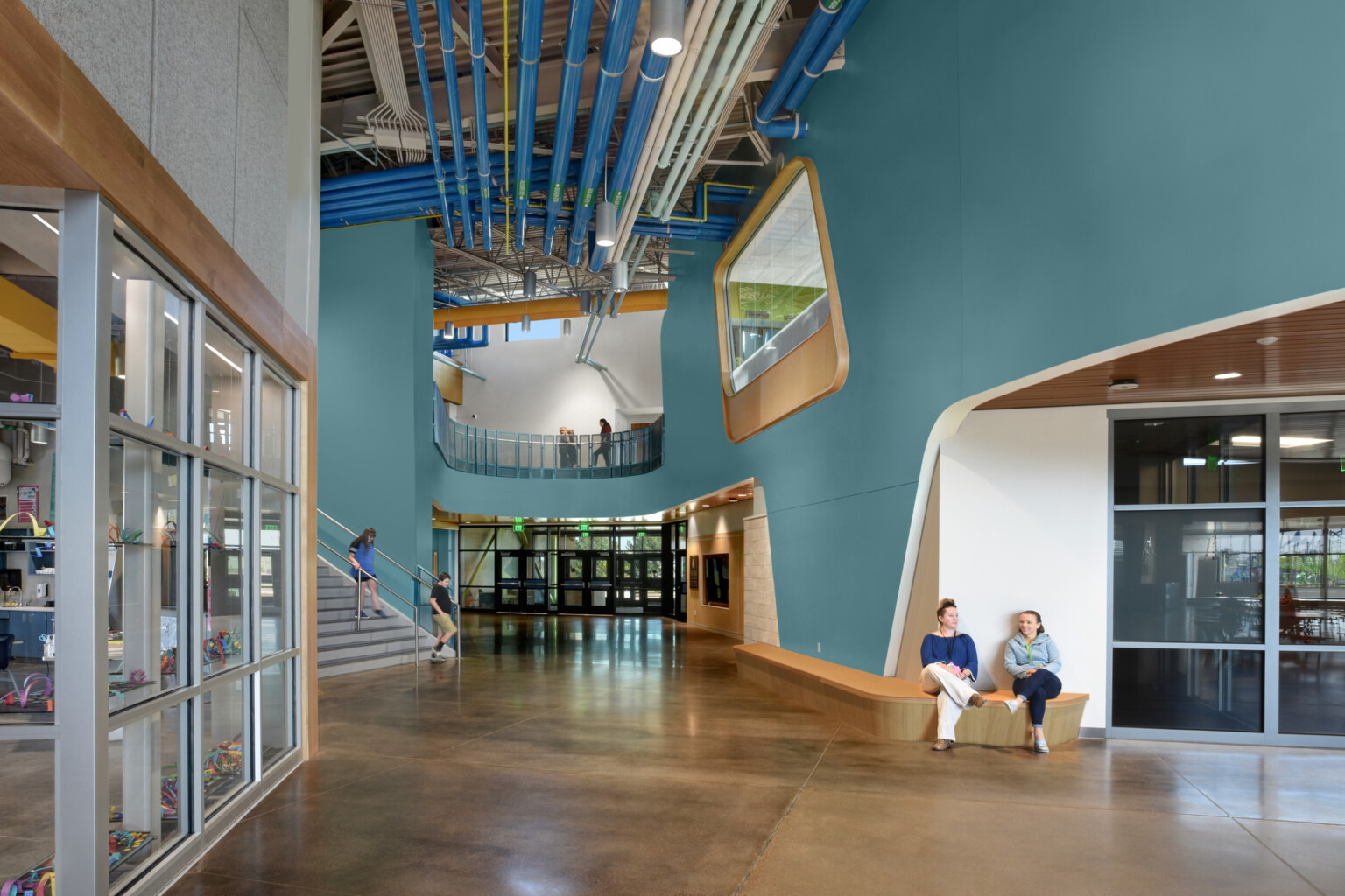 hallway of an early education school with large double height walls and overlooks; blue and orange colors throughout the space
