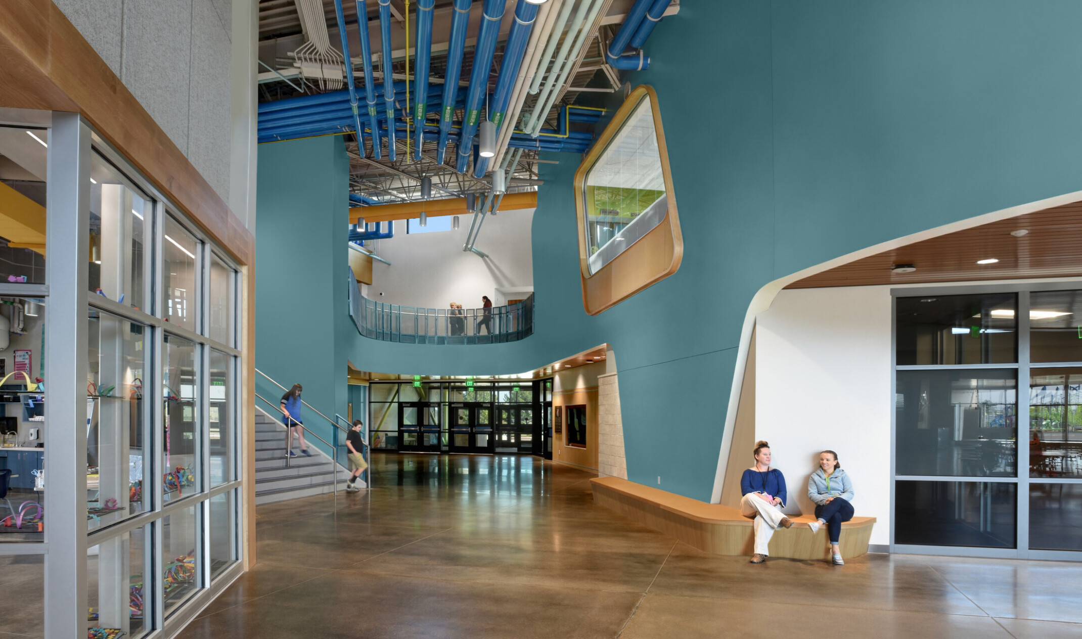 hallway of an early education school with large double height walls and overlooks; blue and orange colors throughout the space