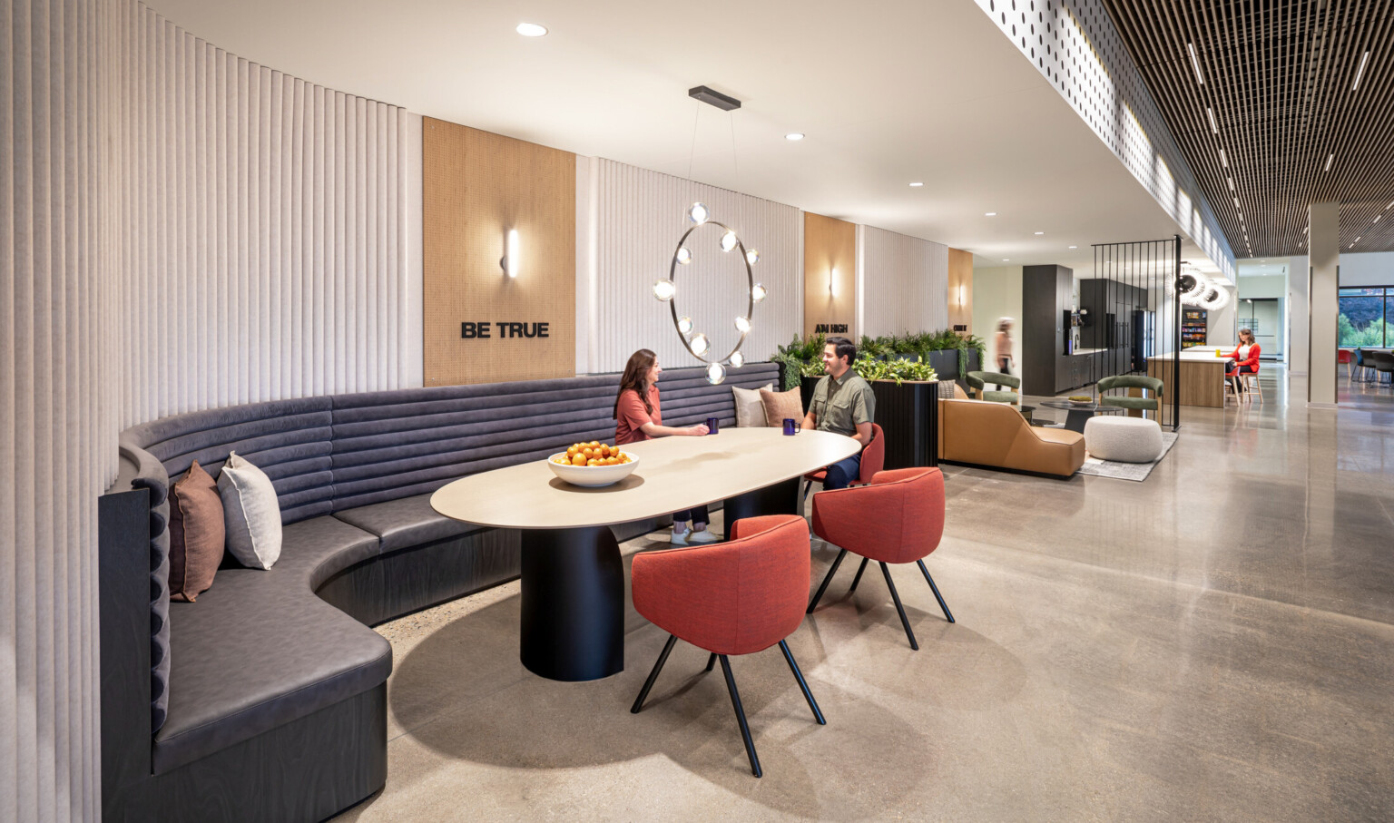 The Spine at Particle Measuring Systems, a large work café with curved seating groups, biophilic plantings, and displays of the company’s core values where manufacturing, engineering, and services teams come together